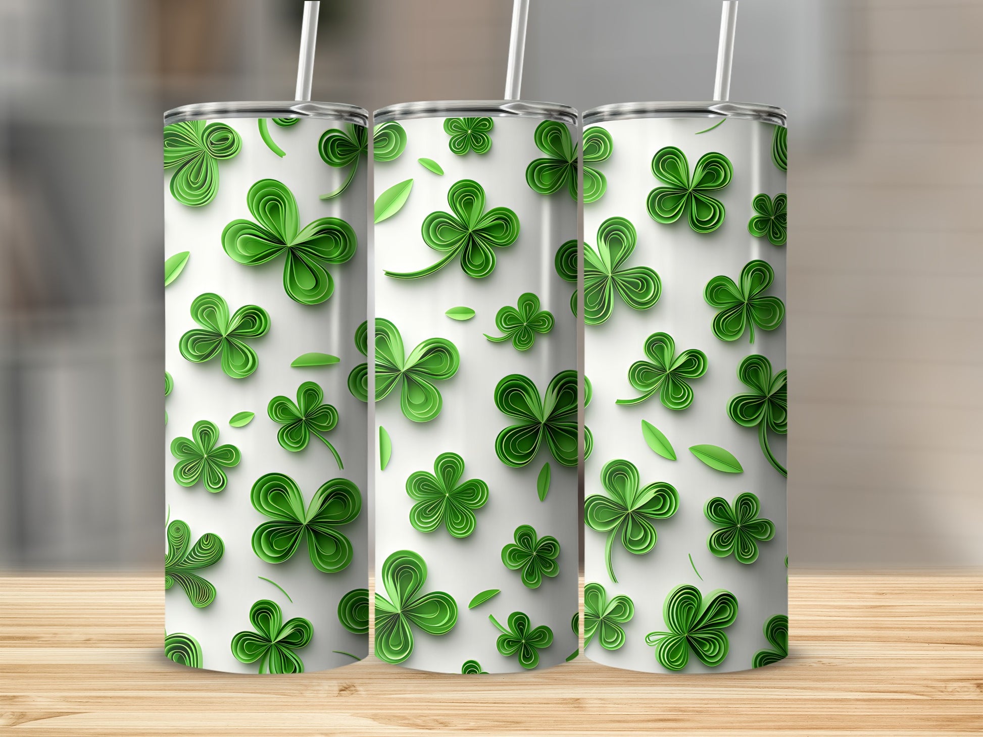 Three green shamrock pattern tumblers with straws on a wooden surface.