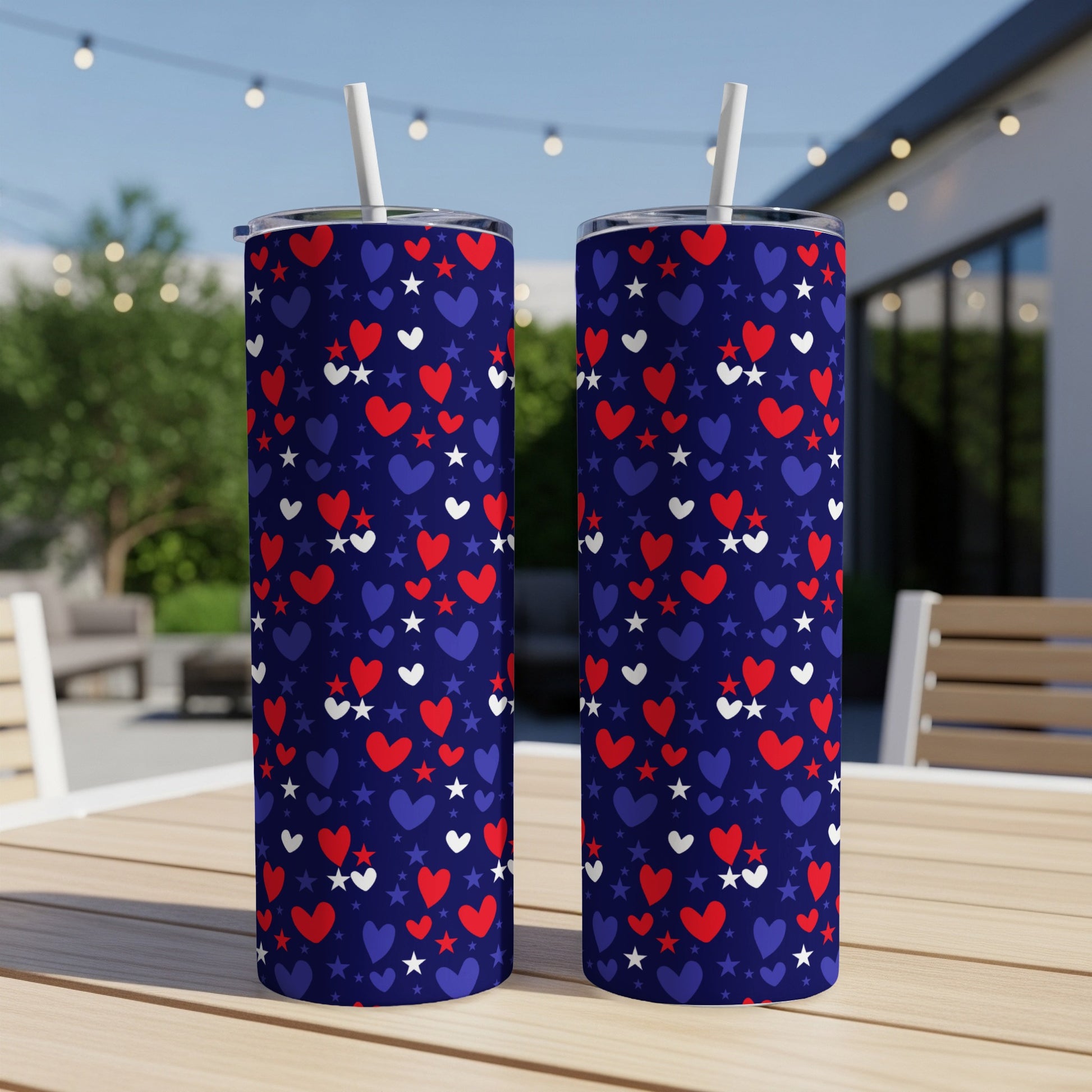 Two navy blue tumblers with red and white hearts and stars, on a table.