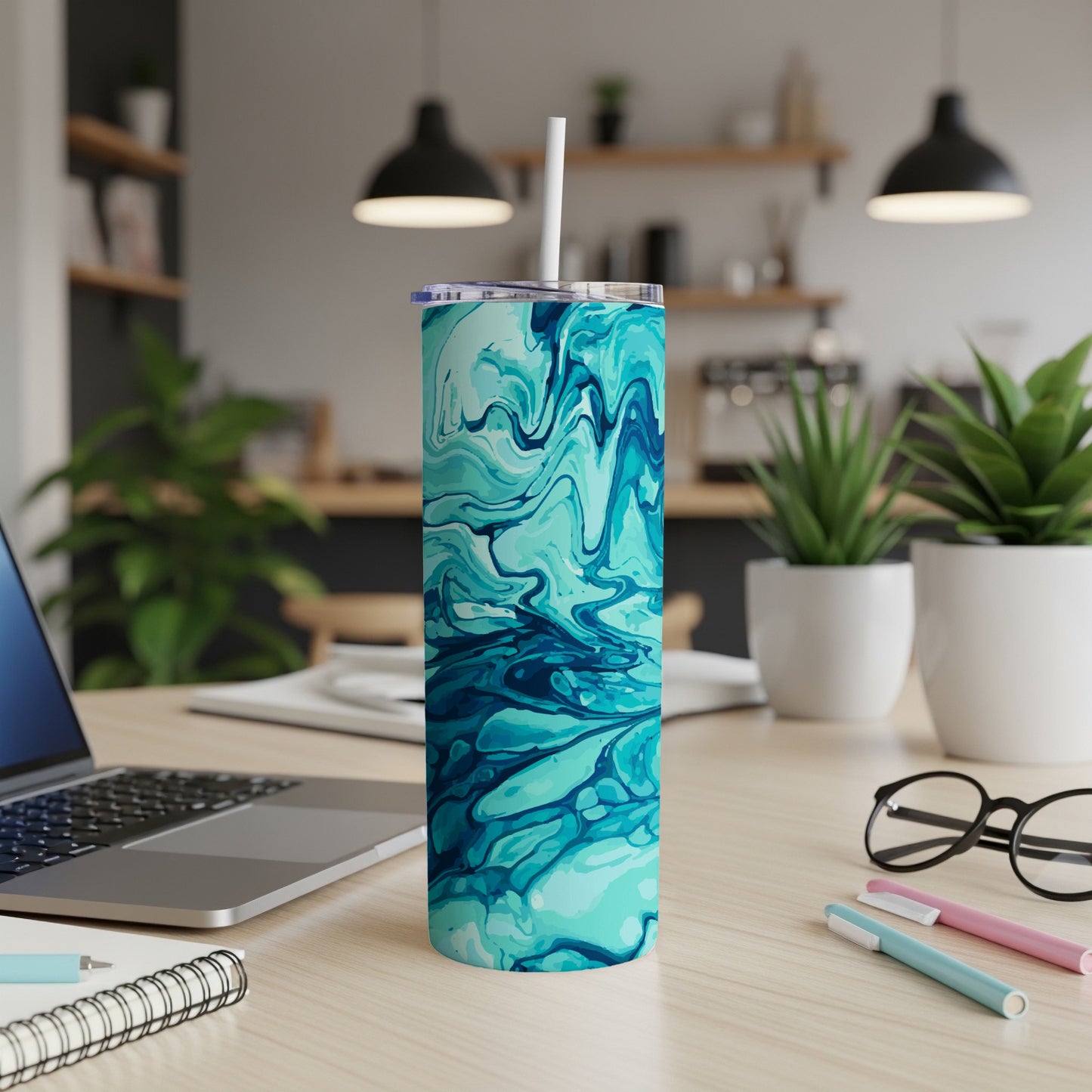 Tall tumbler with blue and teal marbled design and white straw on desk.