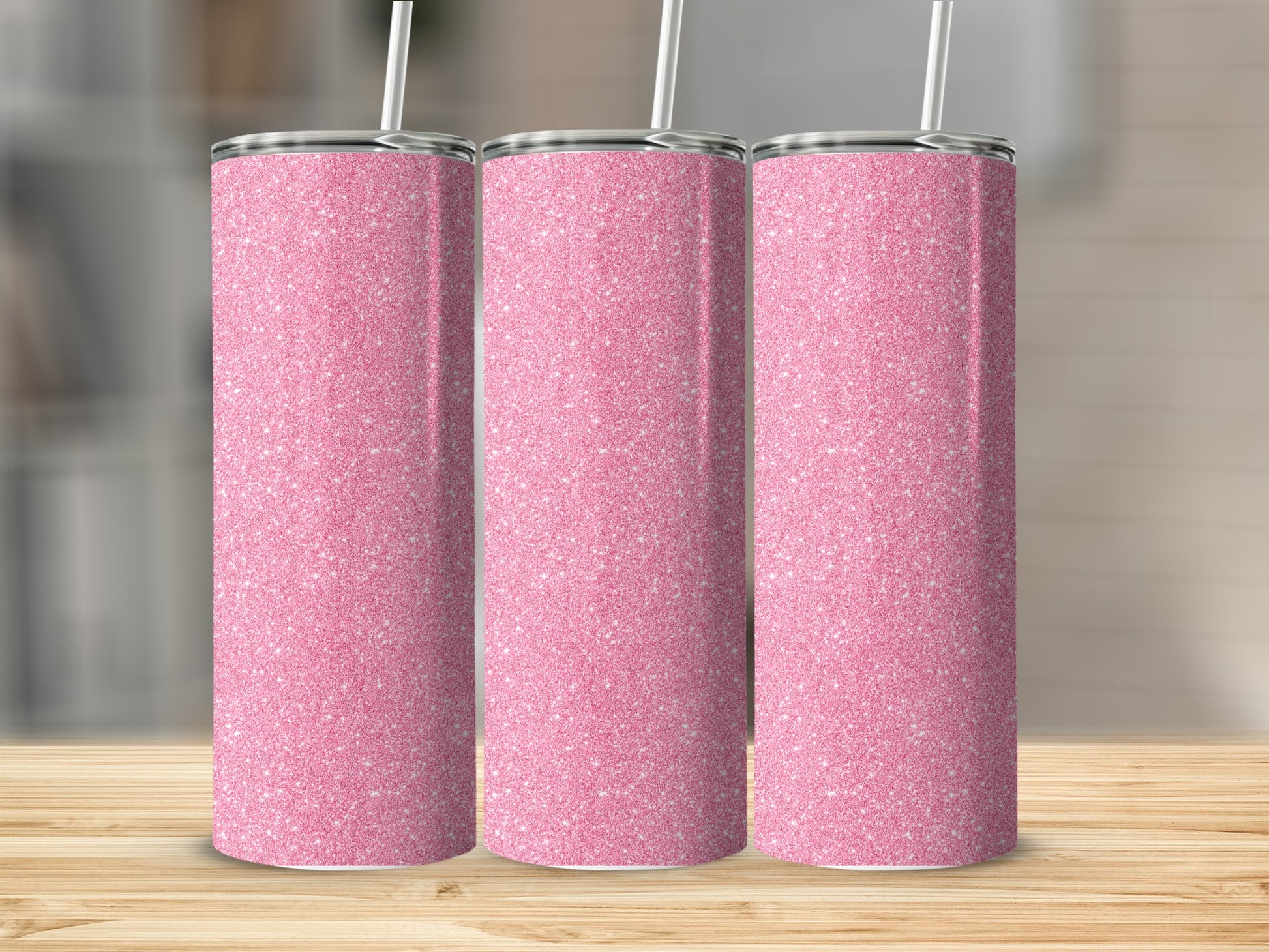 Three pink glitter tumblers with straws on a wooden surface.