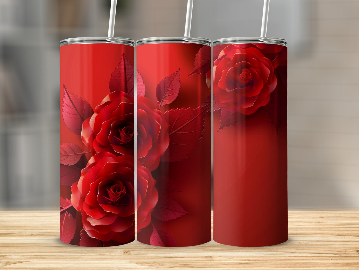 Three red tumblers with rose designs on a wooden surface.