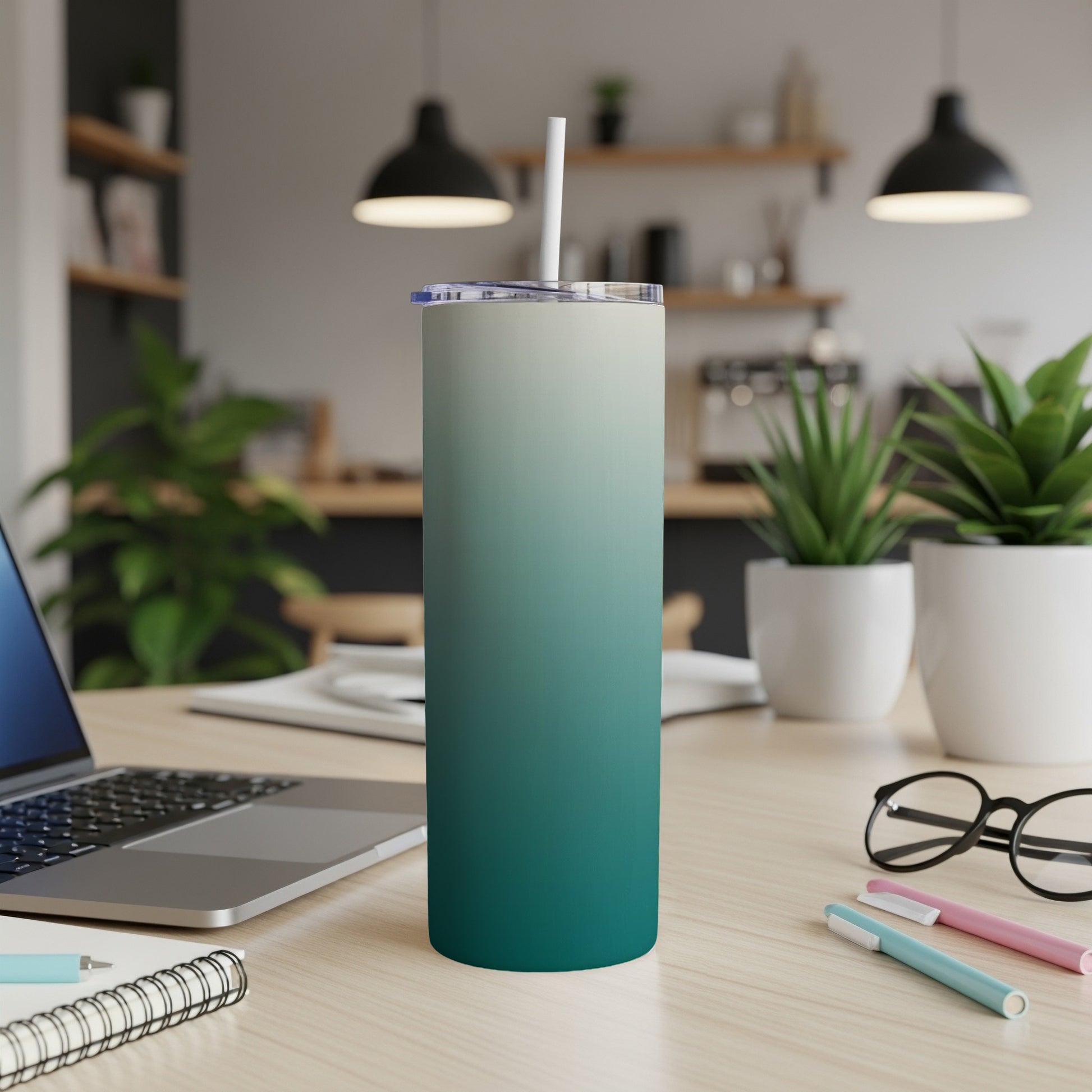 Gradient teal and cream tumbler with straw on a wooden desk.