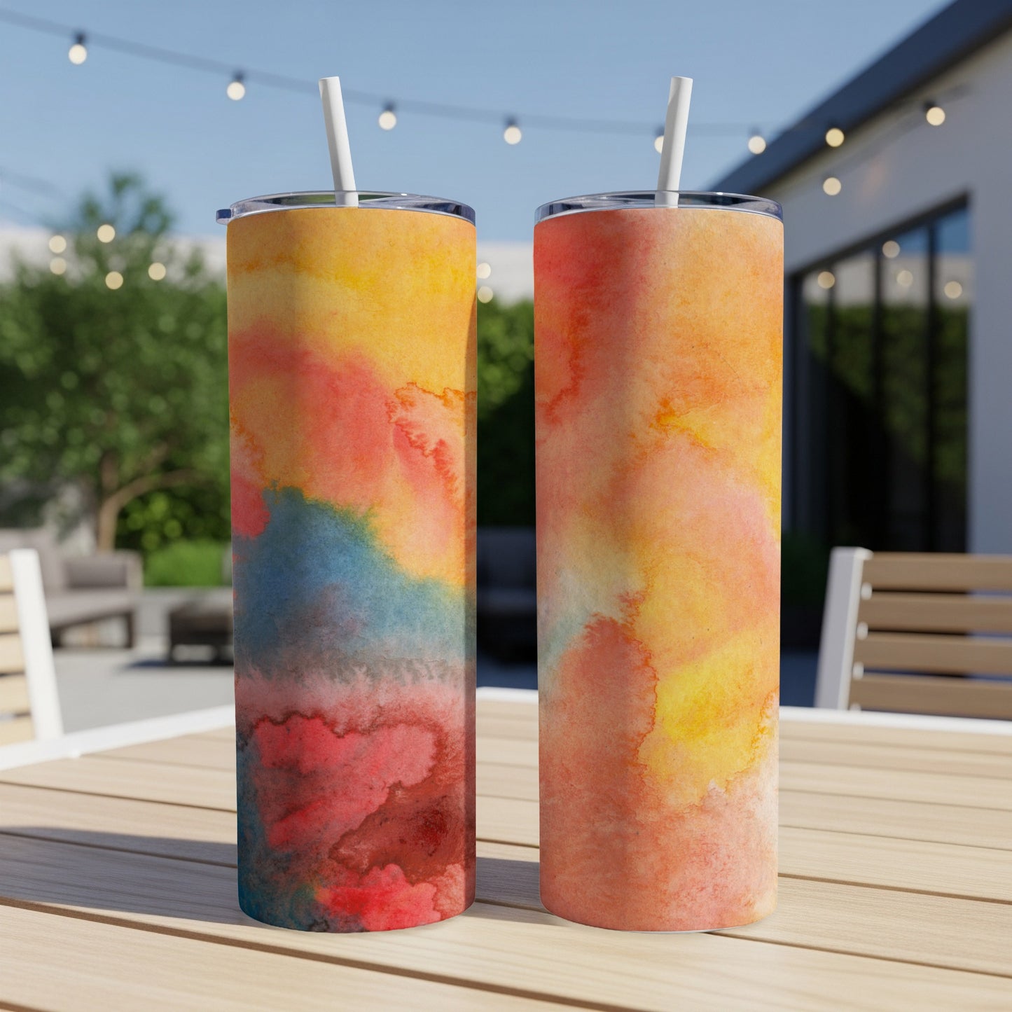 Two tumblers with watercolor designs of red, blue, and yellow on a wooden table.