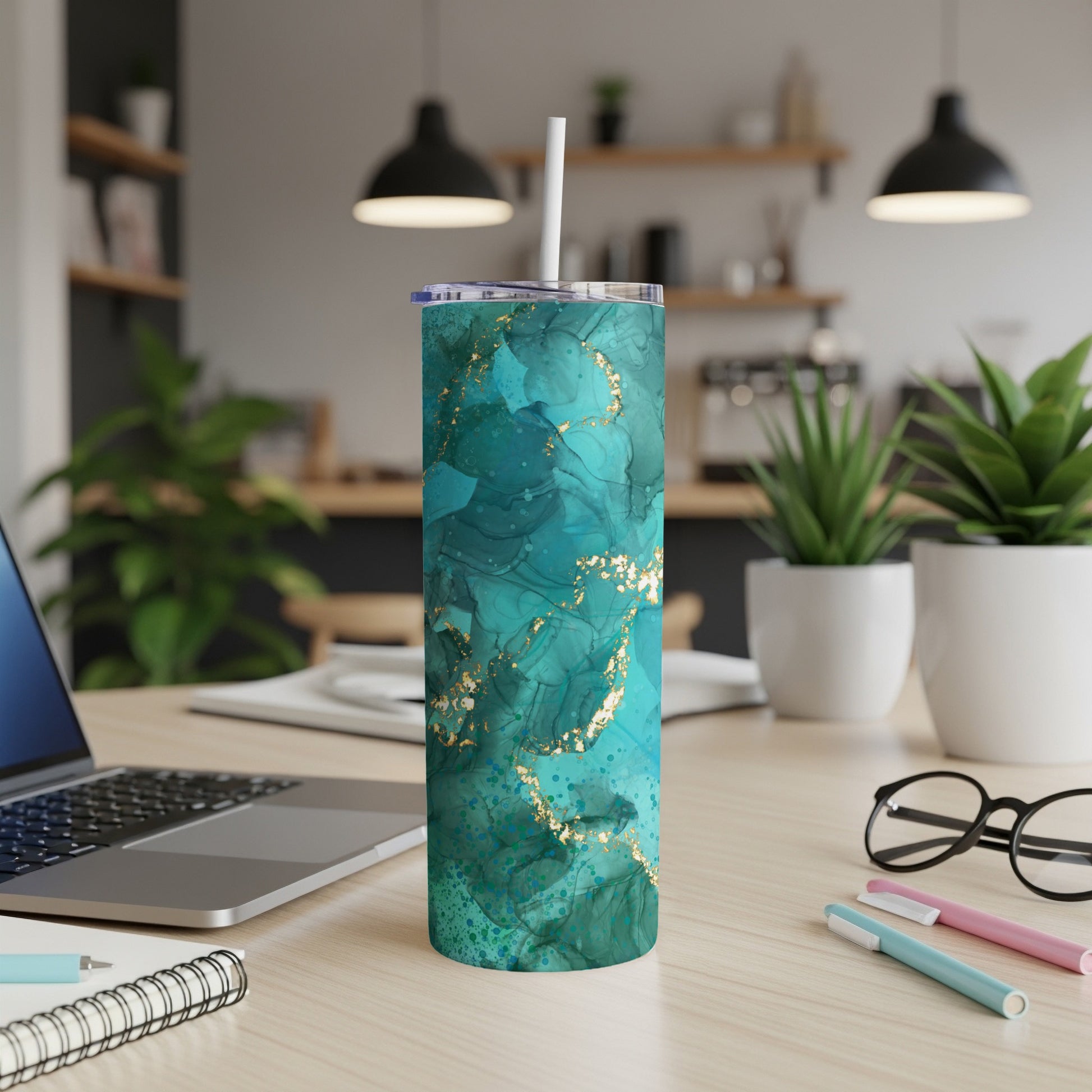 Turquoise and gold marble pattern tumbler with straw on desk.