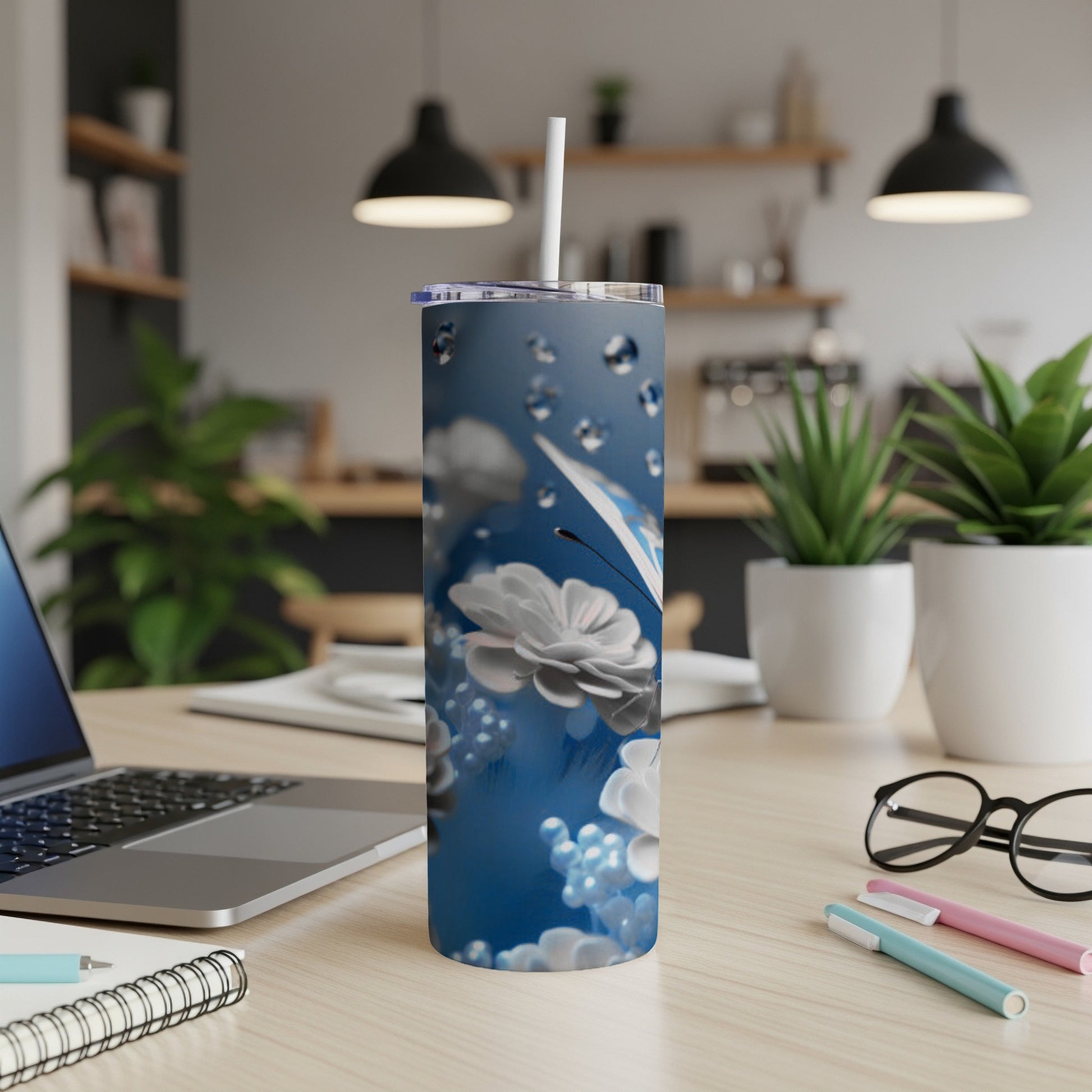 Blue tumbler with white flowers and water droplets, straw in lid.