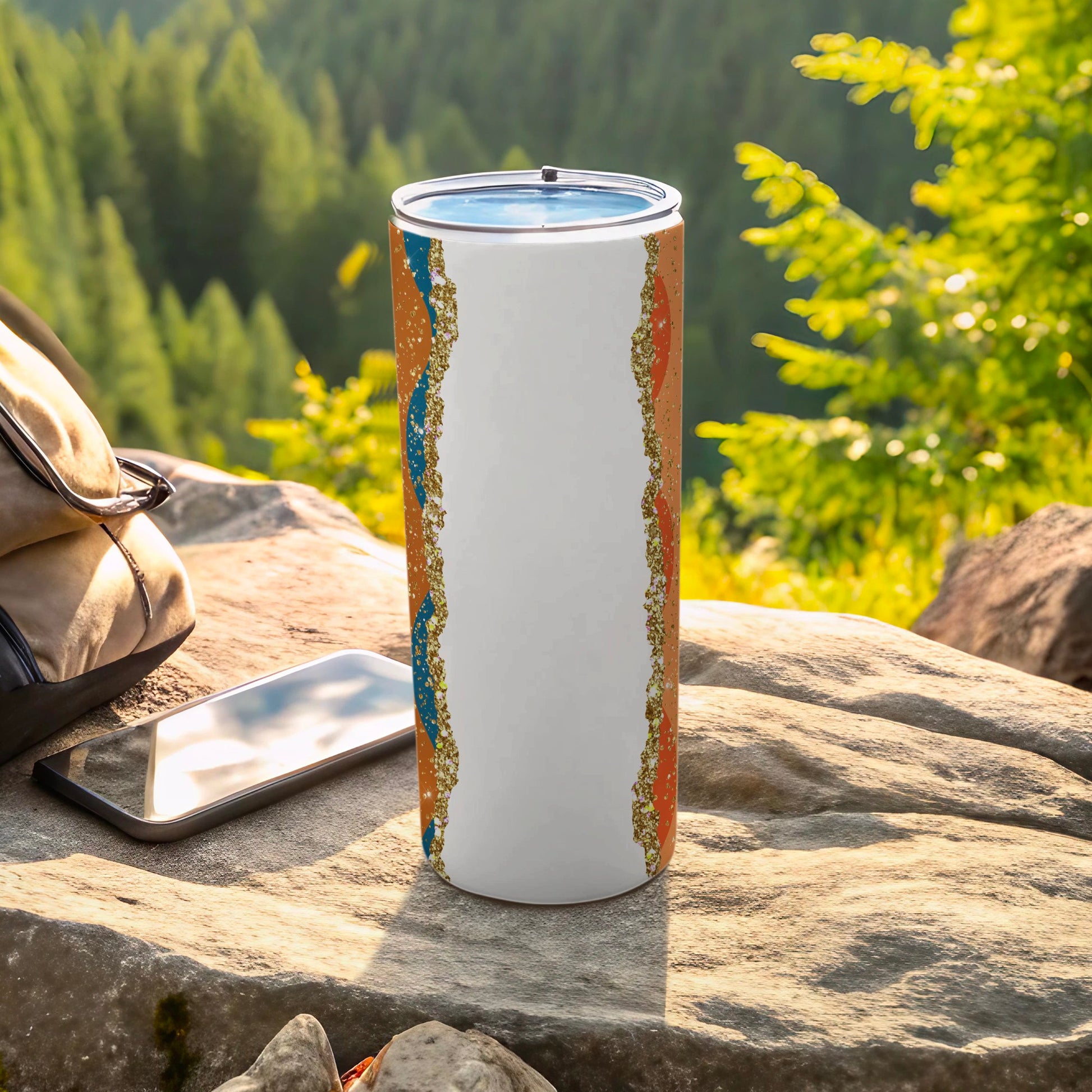 White tumbler with abstract orange and blue wavy pattern on rocky outcrop.