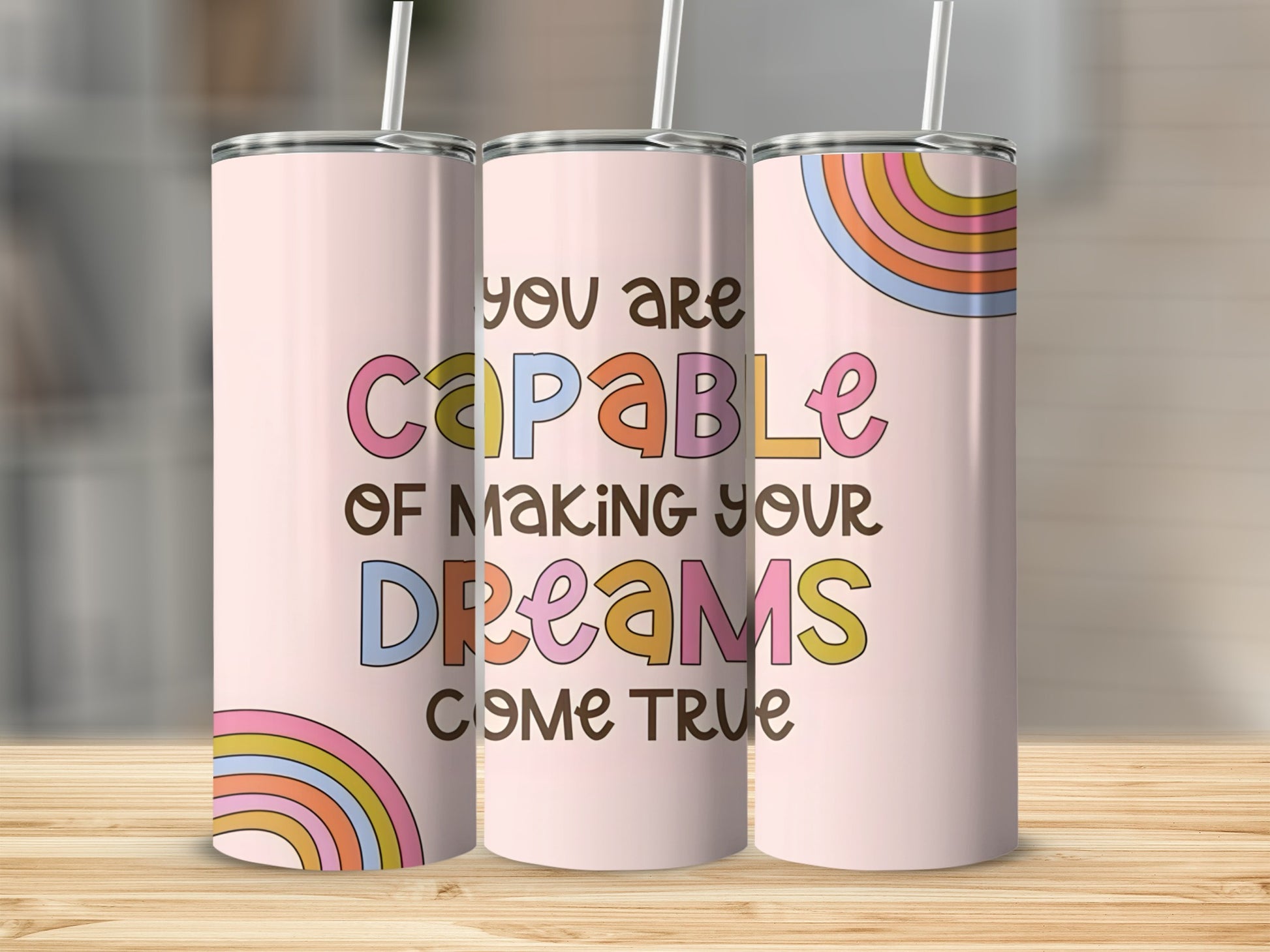 Pink tumbler with "You are capable of making your dreams come true" text and rainbow accents.