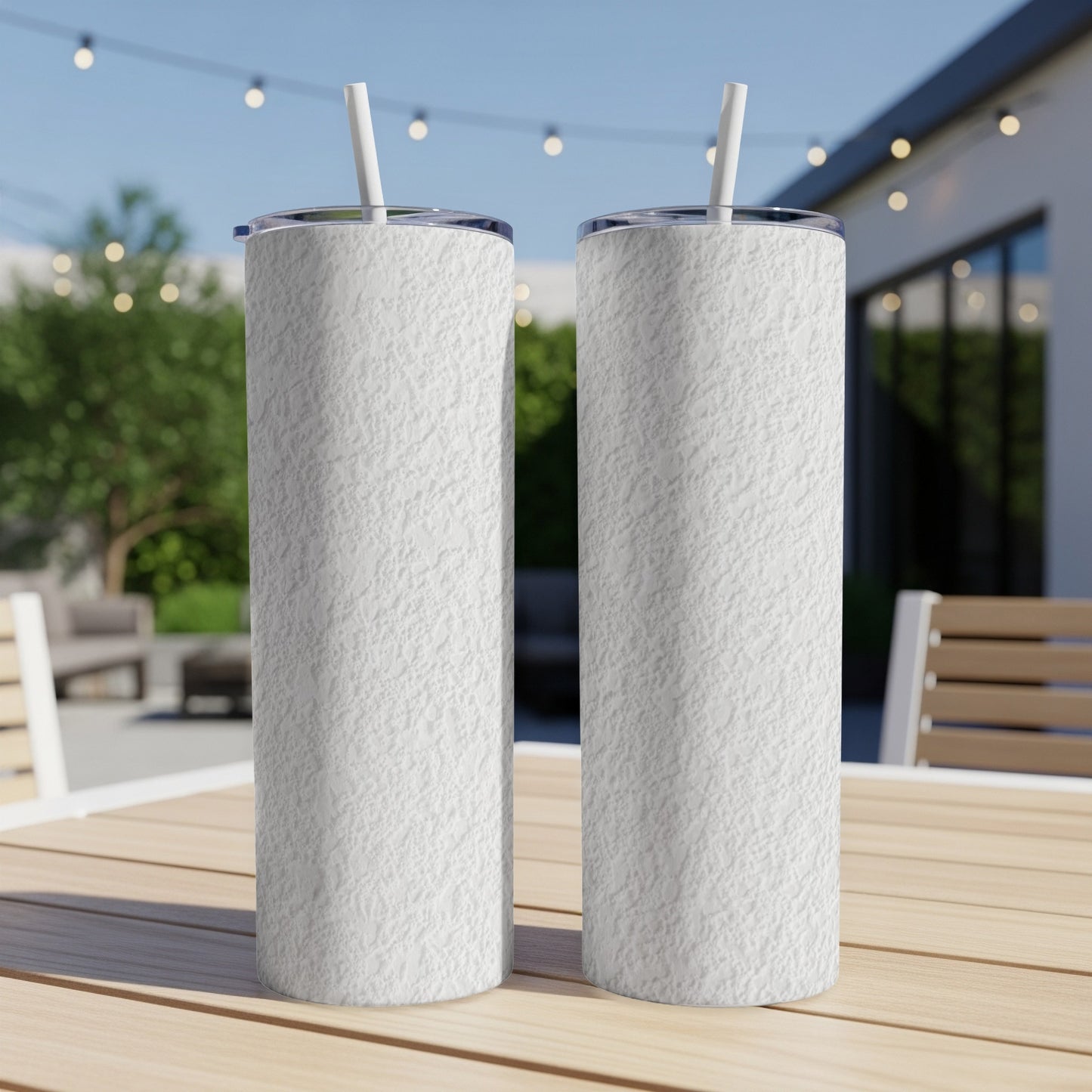 Two white textured tumblers with straws sit on a wooden table.