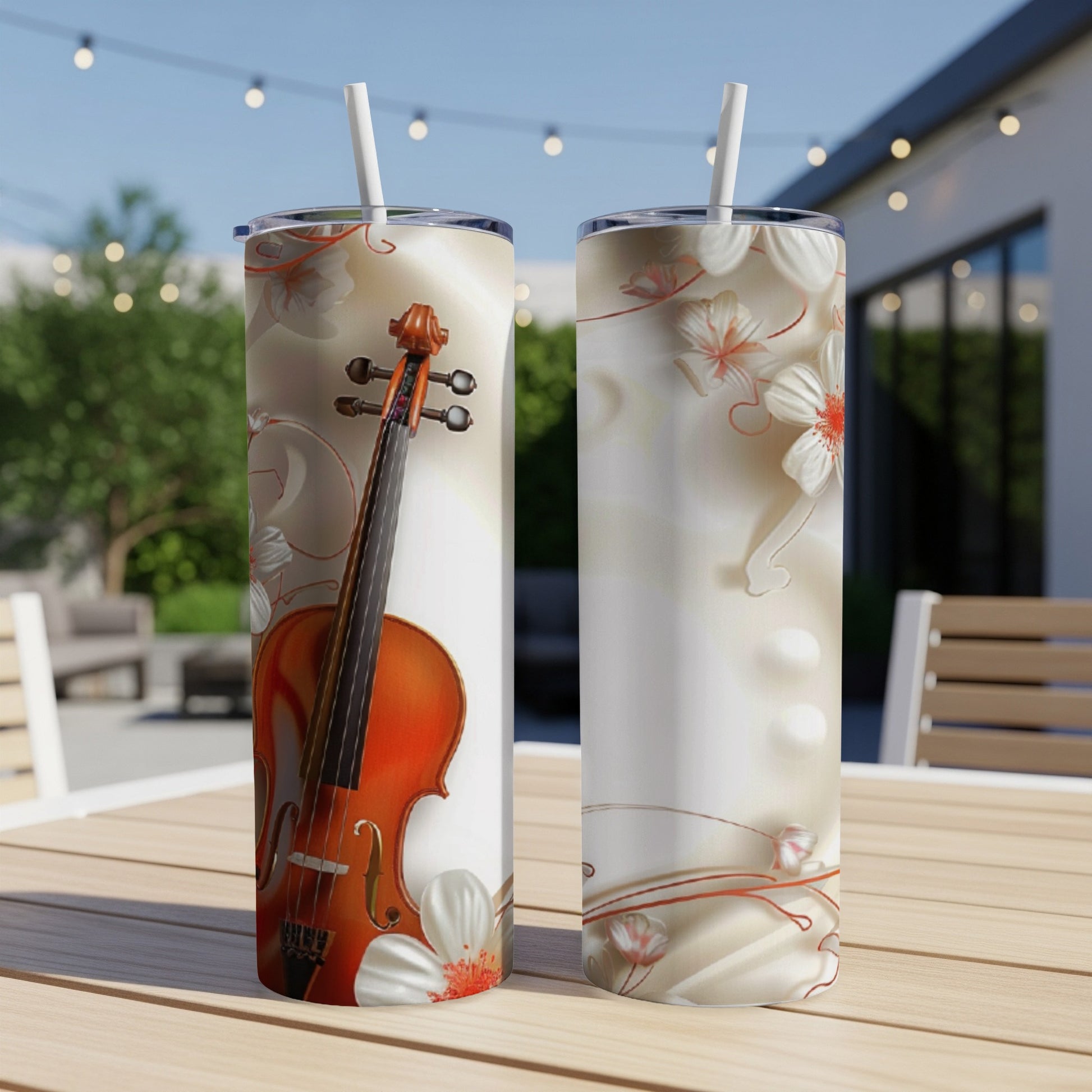 Two tumblers with violin and floral design on an outdoor table.