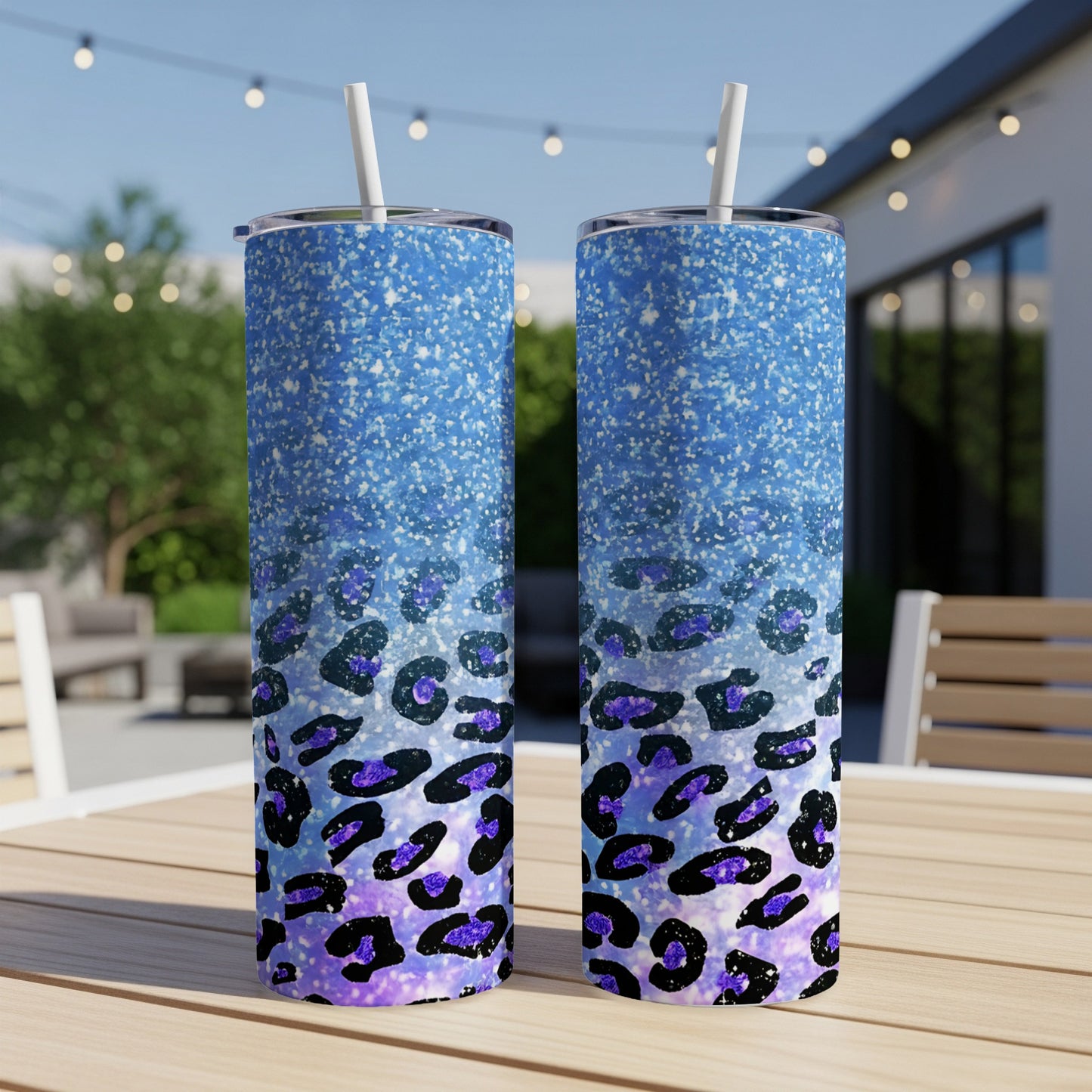 Two blue glitter tumblers with purple leopard print design on a wooden table.