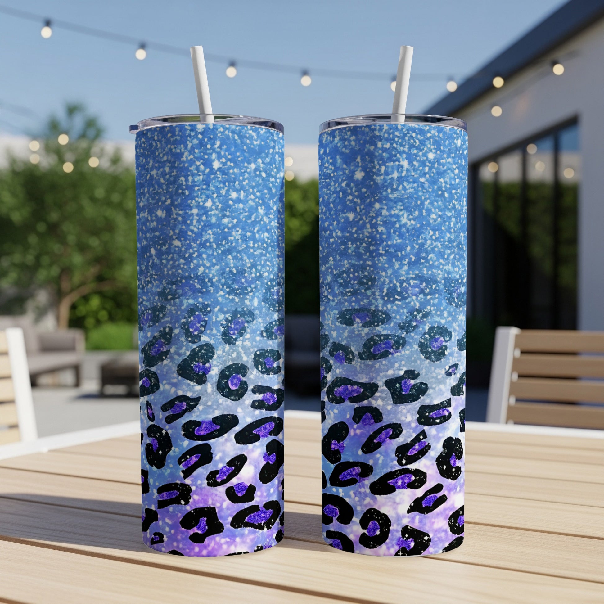 Two blue glitter tumblers with purple leopard print design on a wooden table.