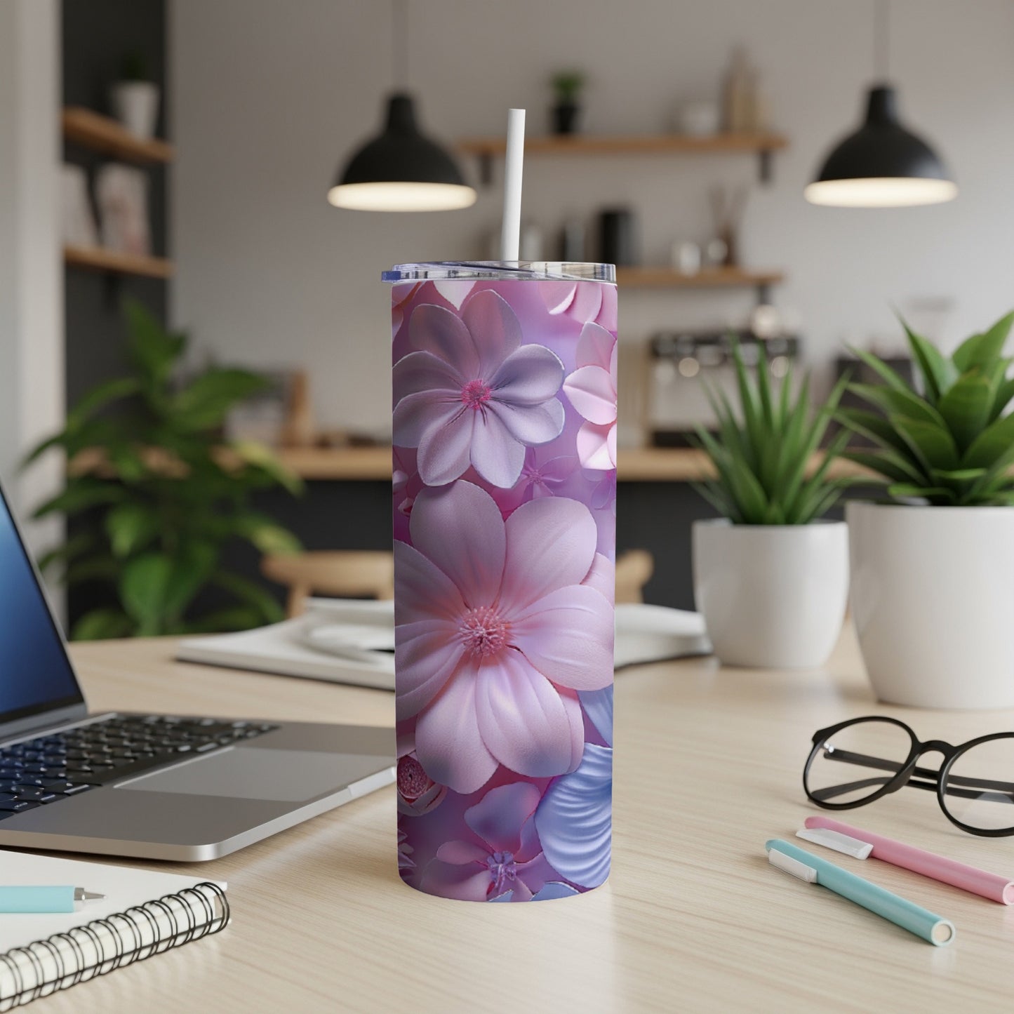 Pink and purple floral tumbler with straw on a desk.