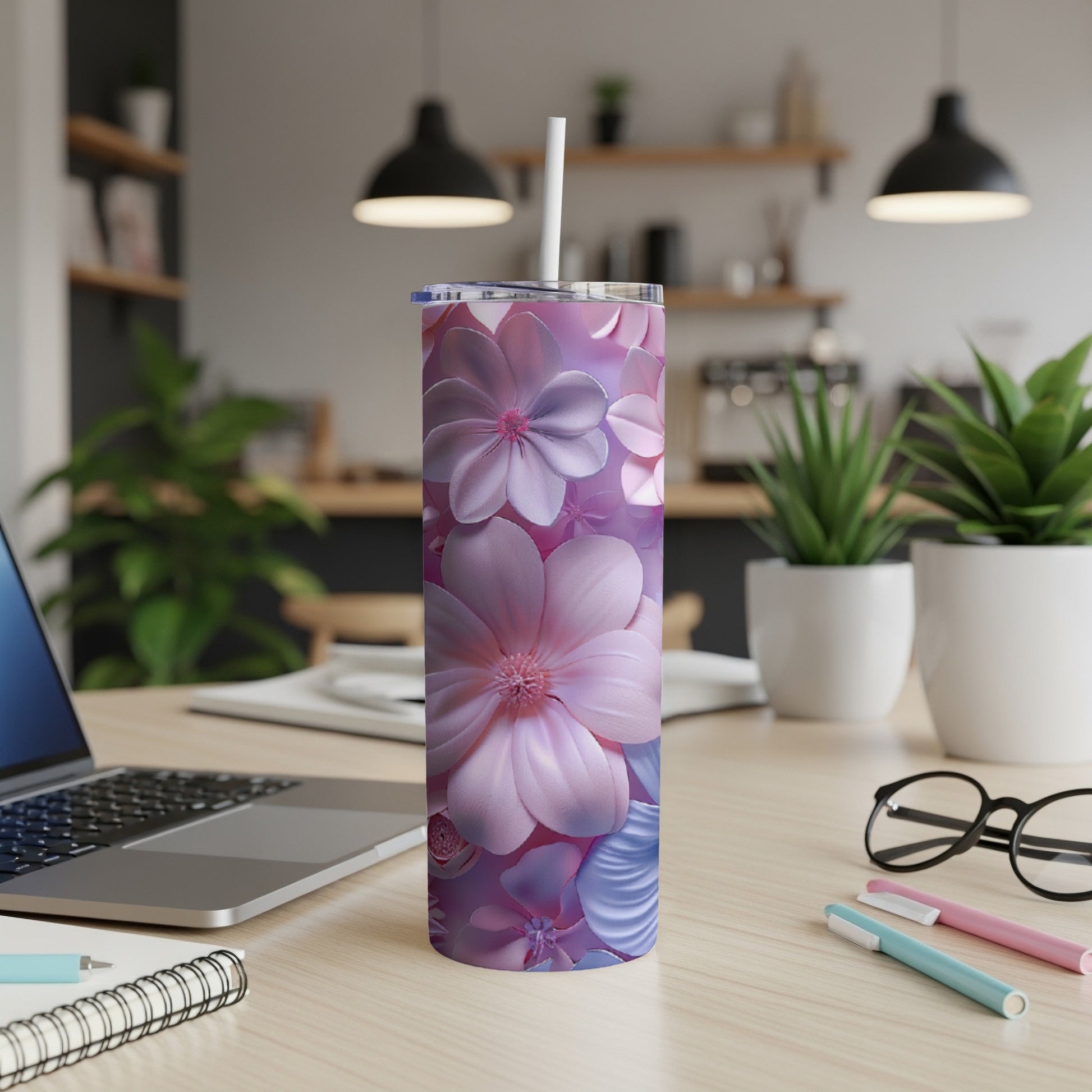 Pink and purple floral tumbler with straw on a desk.