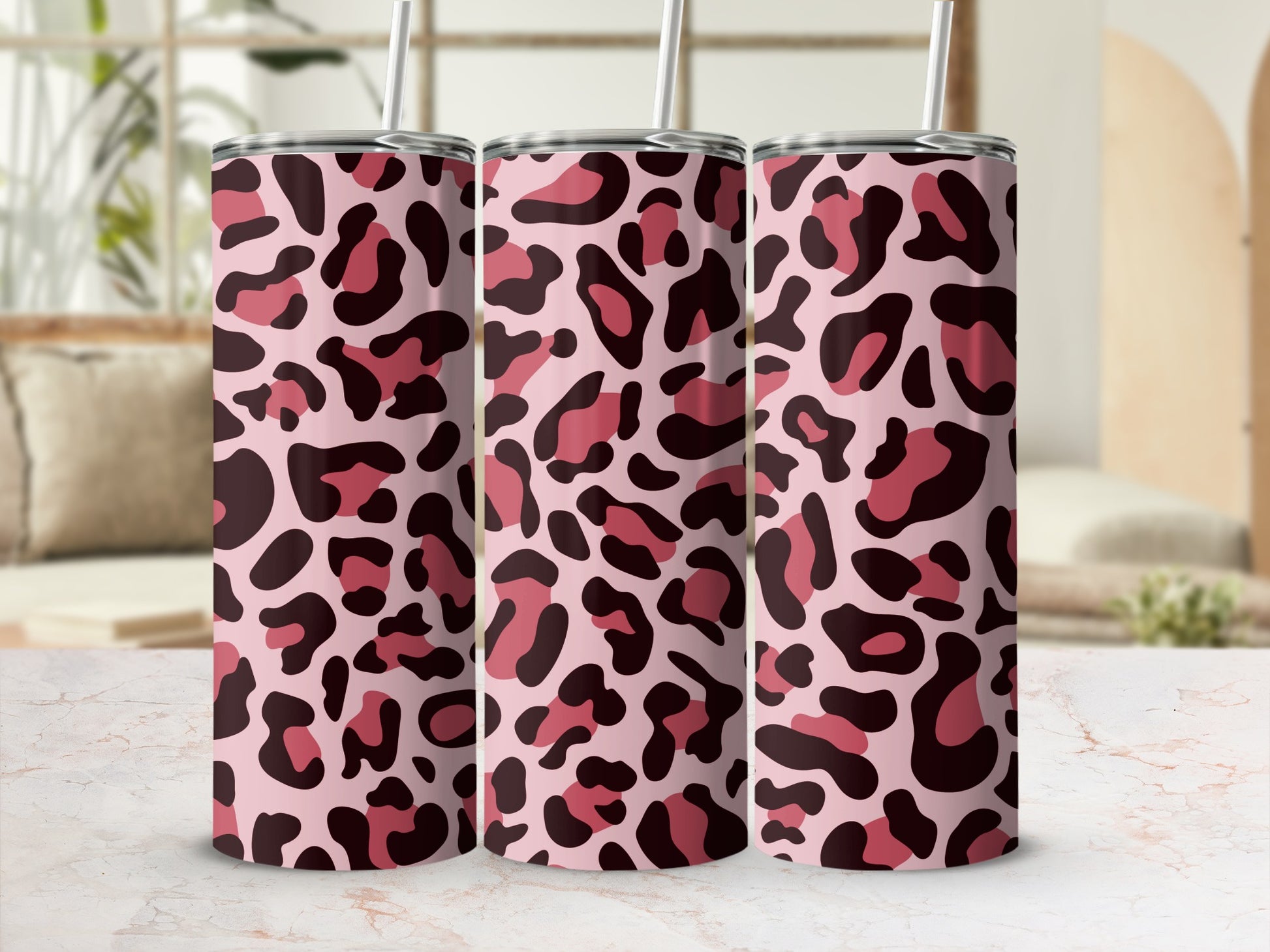 Three pink tumblers with a leopard print design and straws.