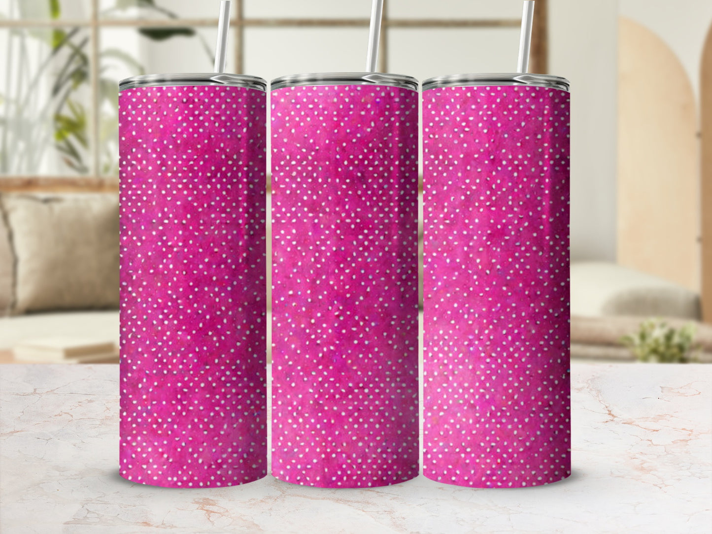 Three pink tumblers with white polka dots on a marble surface.