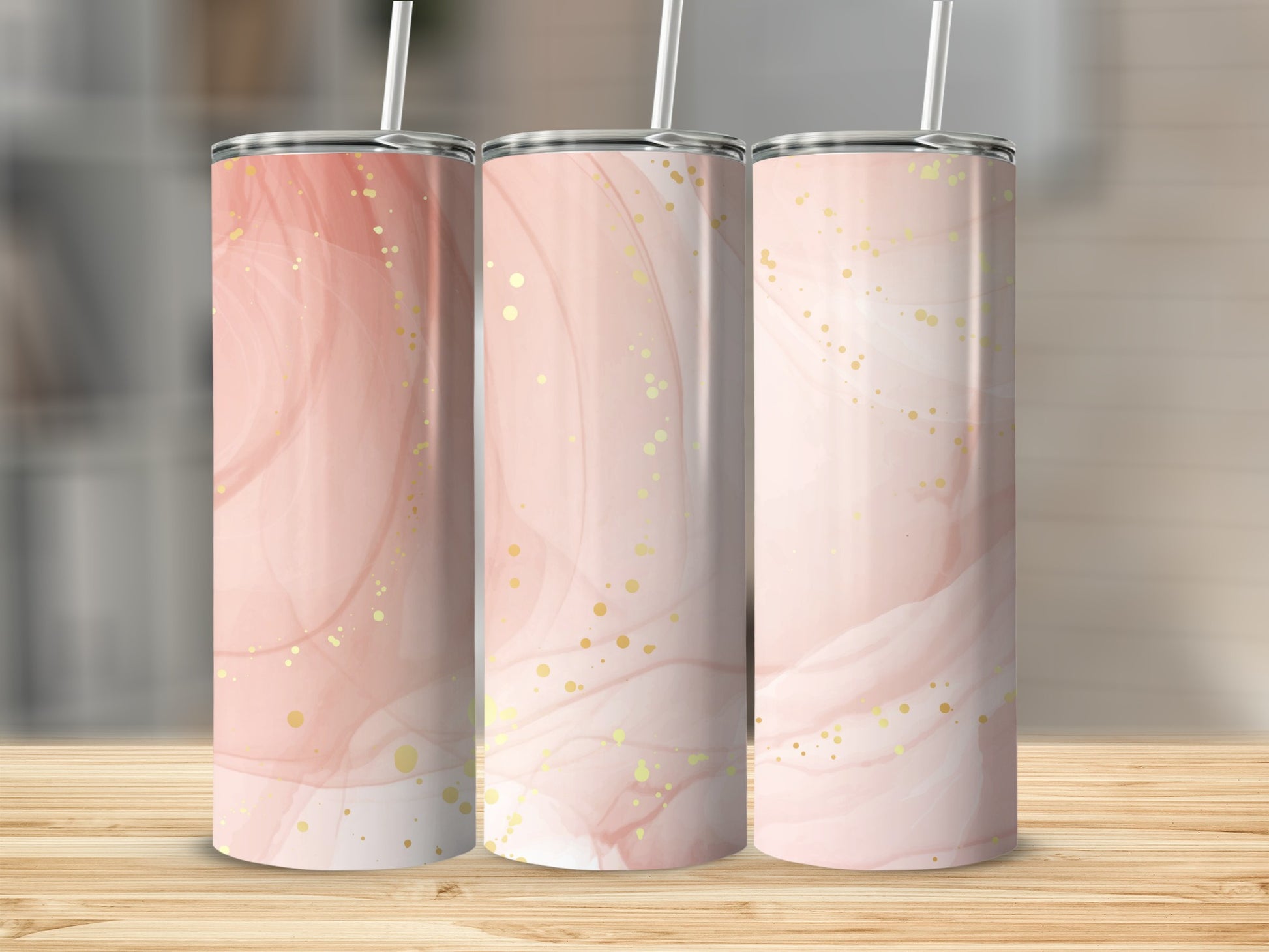 Three tumblers with pink and gold watercolor abstract design, displayed on wooden surface.