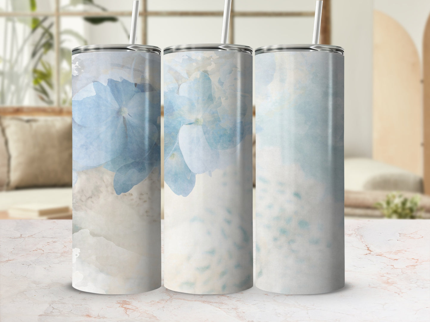 Three tumblers with blue floral watercolor designs on a marble surface.
