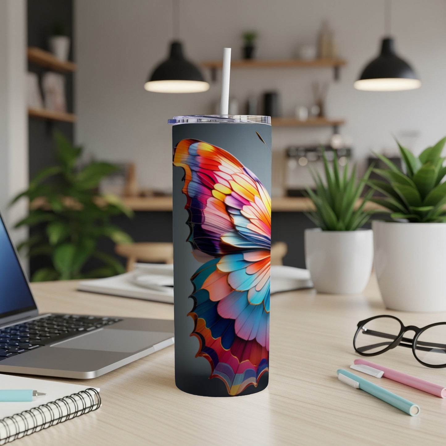 Butterfly wing design on a dark gray tumbler with a straw.