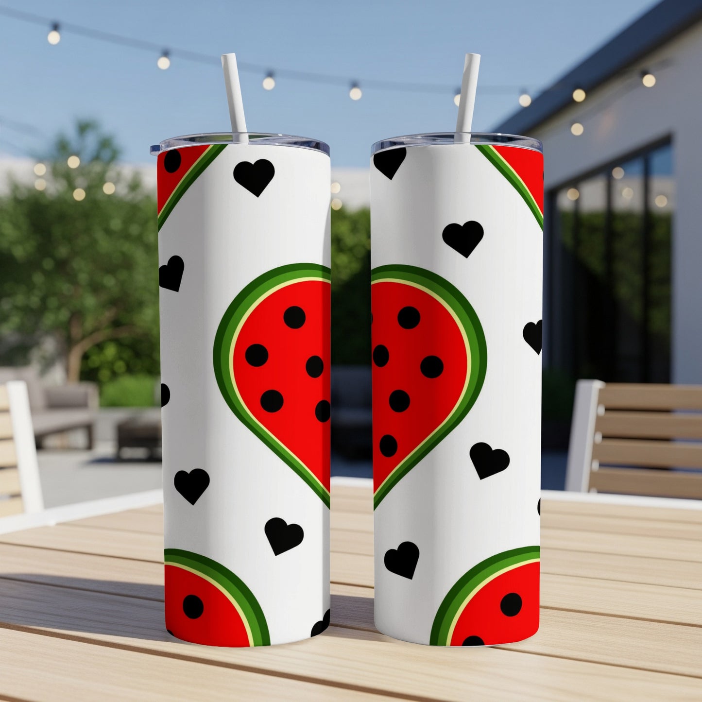 Two white tumblers with watermelon slices and black hearts on outdoor table.