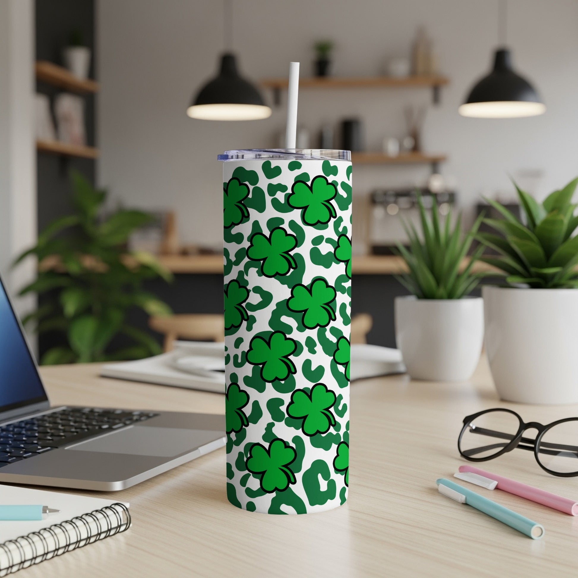 Green shamrock and leopard print tumbler with straw on a desk.