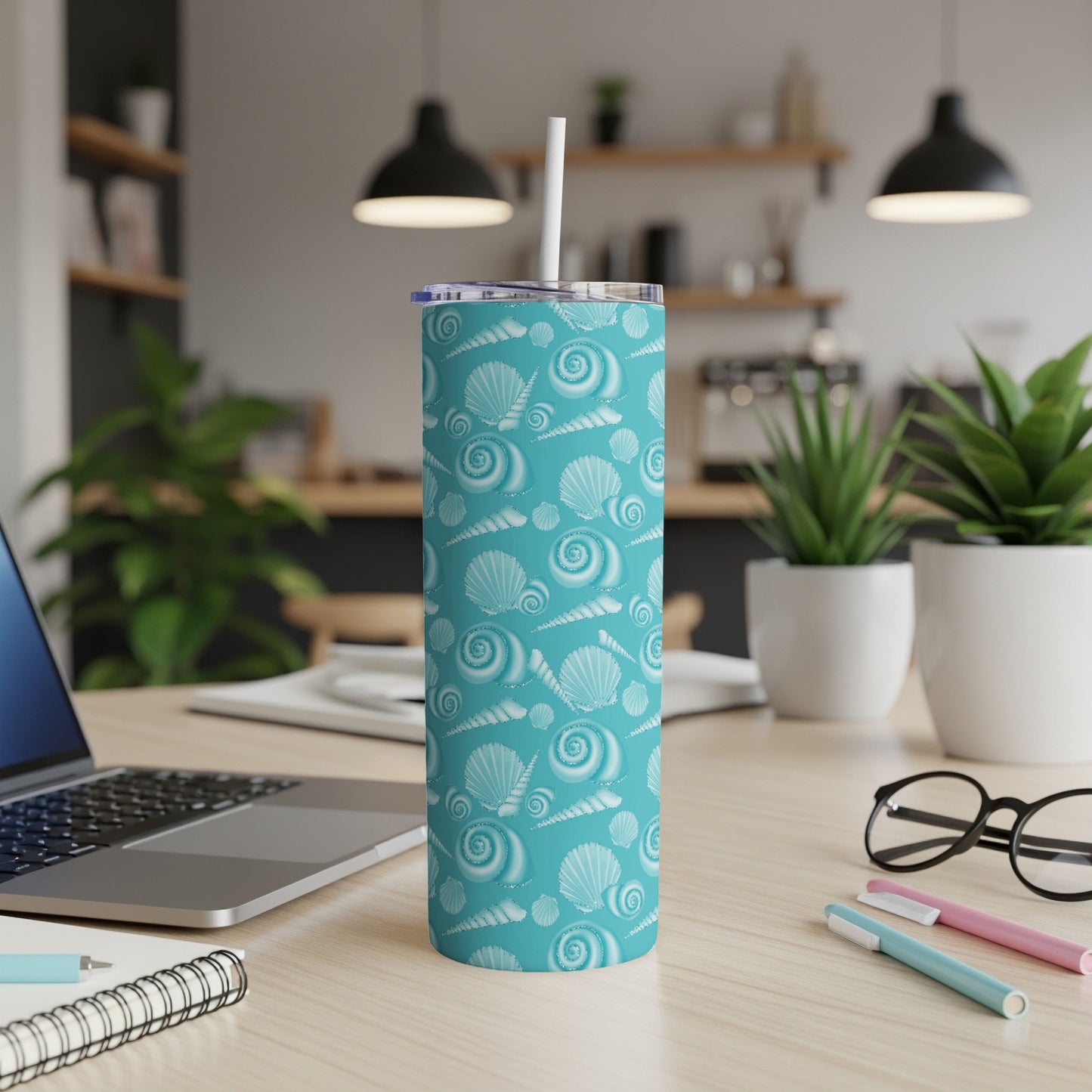 Turquoise tumbler with a seashell pattern and a white straw.