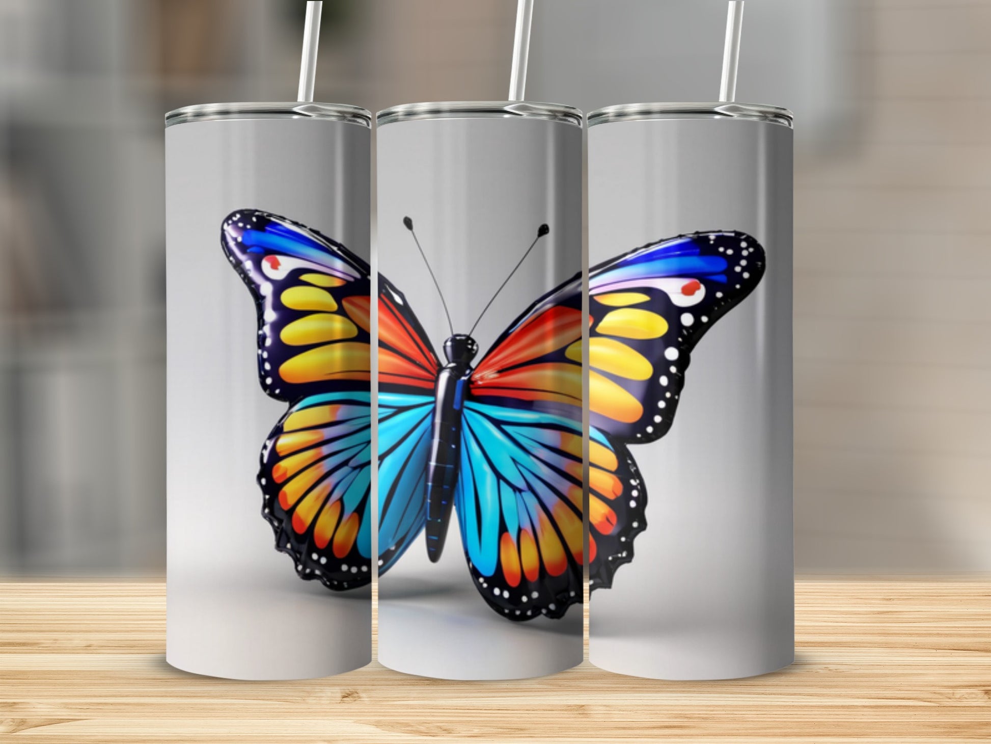 Three tumblers featuring a vibrant butterfly design on a light background.