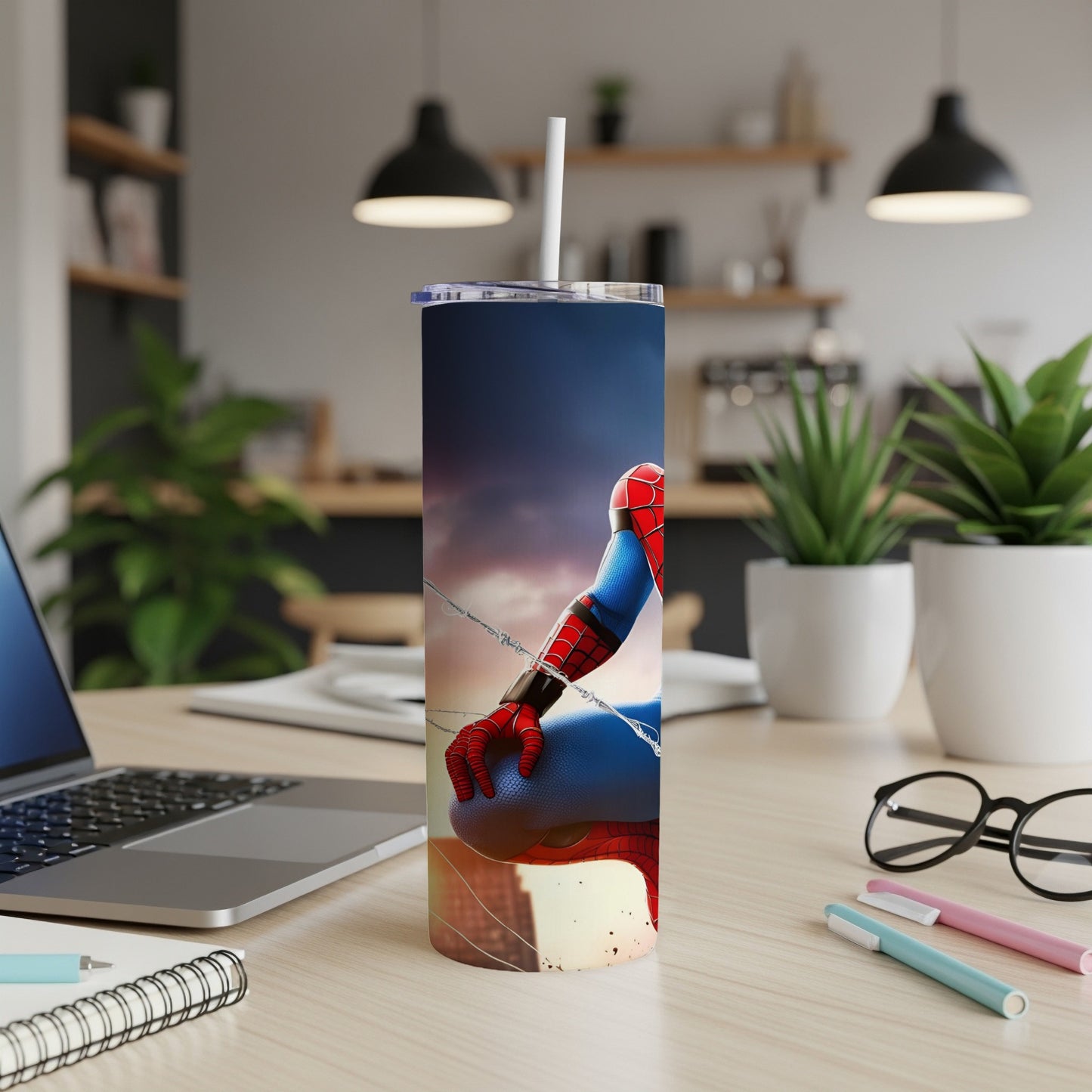 Spiderman reaching out from a tumbler on a desk.