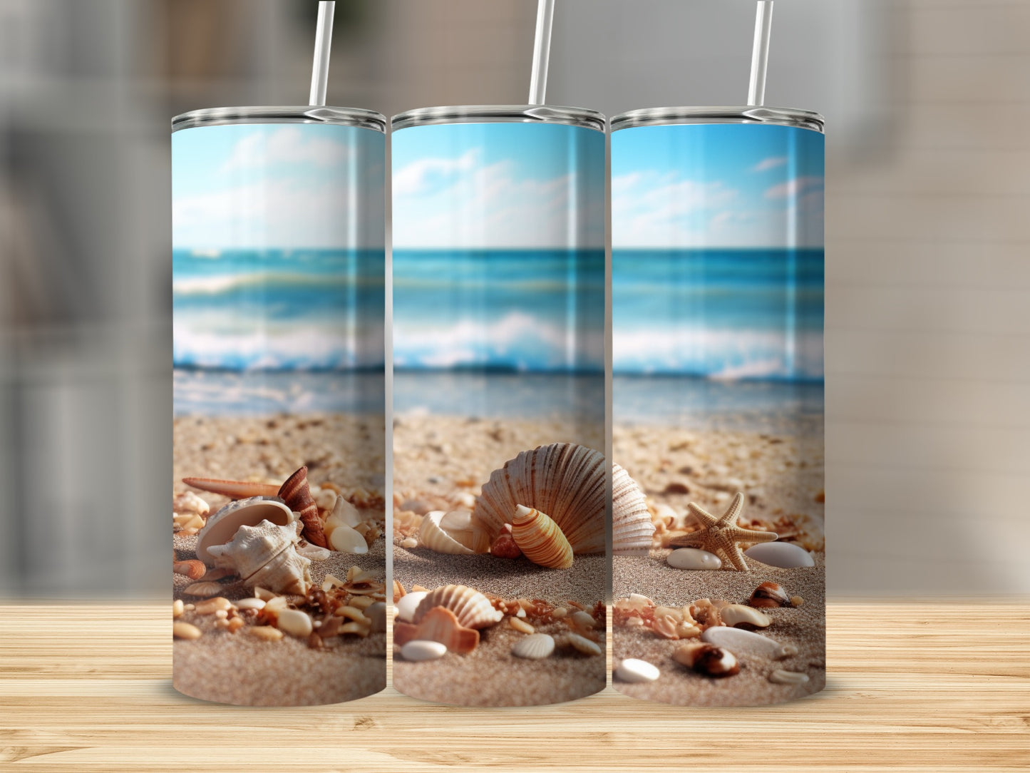 Three tumblers with a beach scene and seashells on sand.