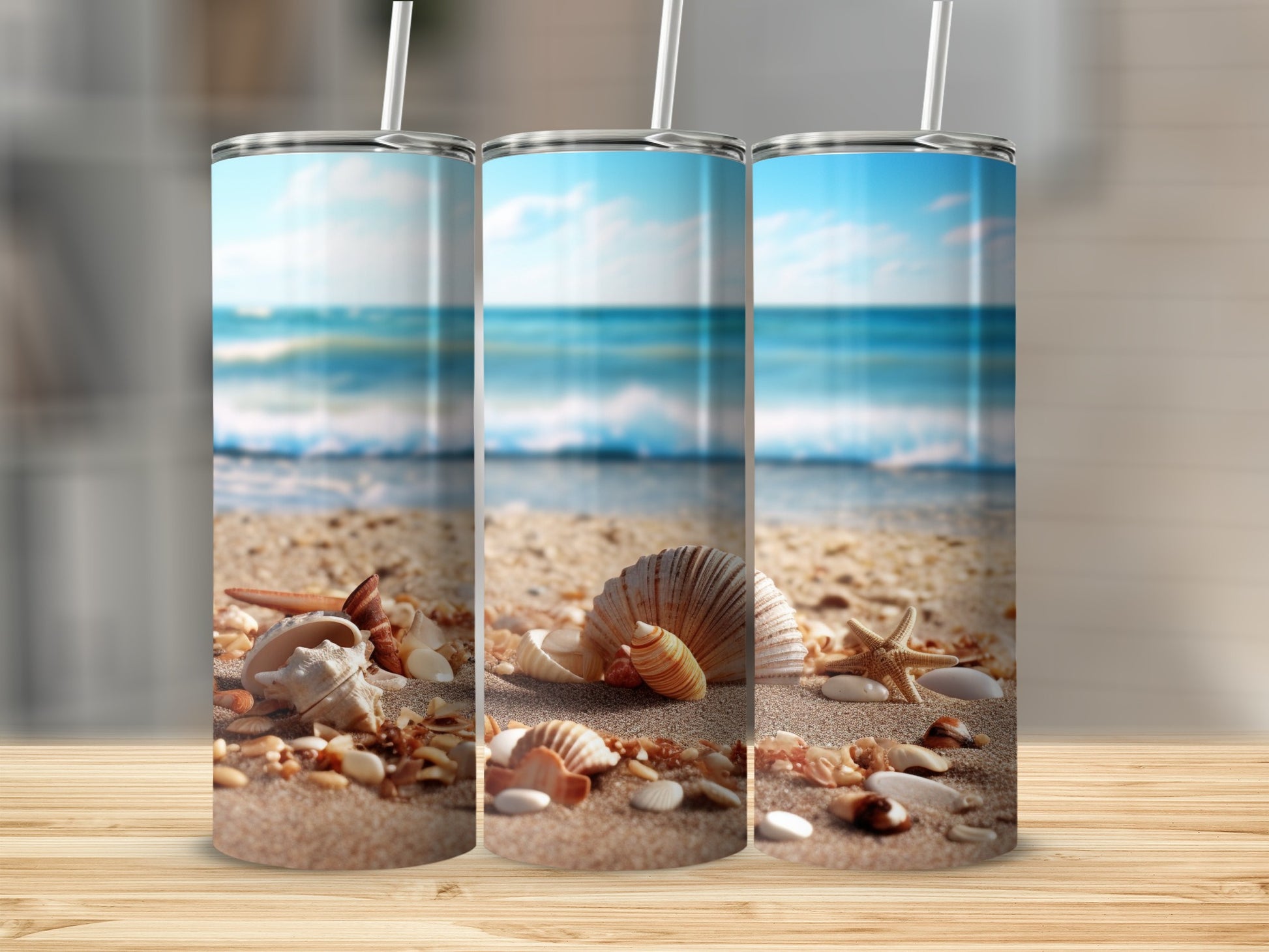 Three tumblers with a beach scene and seashells on sand.