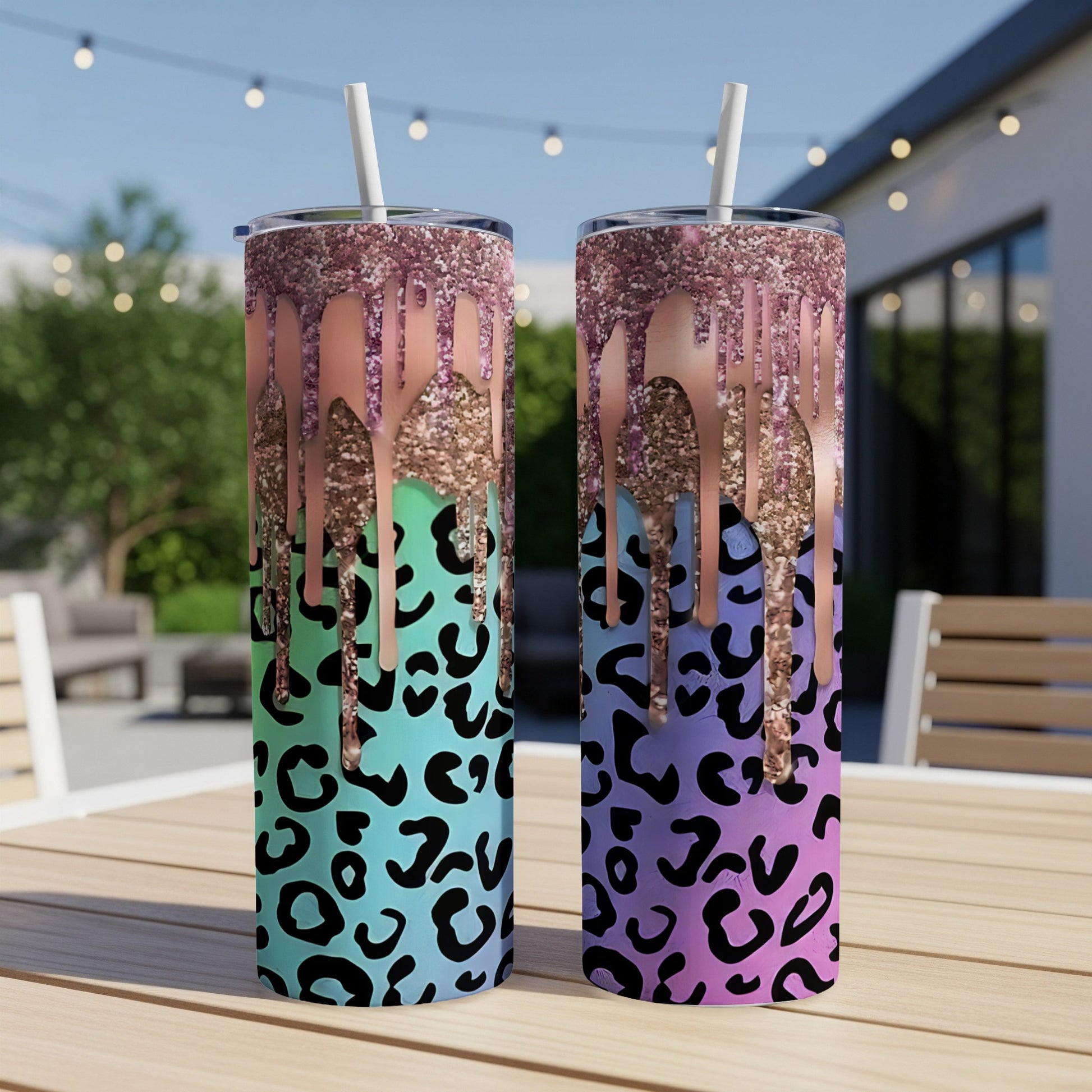 Two glitter-dripped leopard print tumblers with straws on a table.
