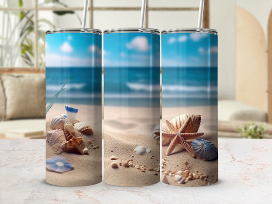Three tumblers with beach and seashell designs on a sandy beach.