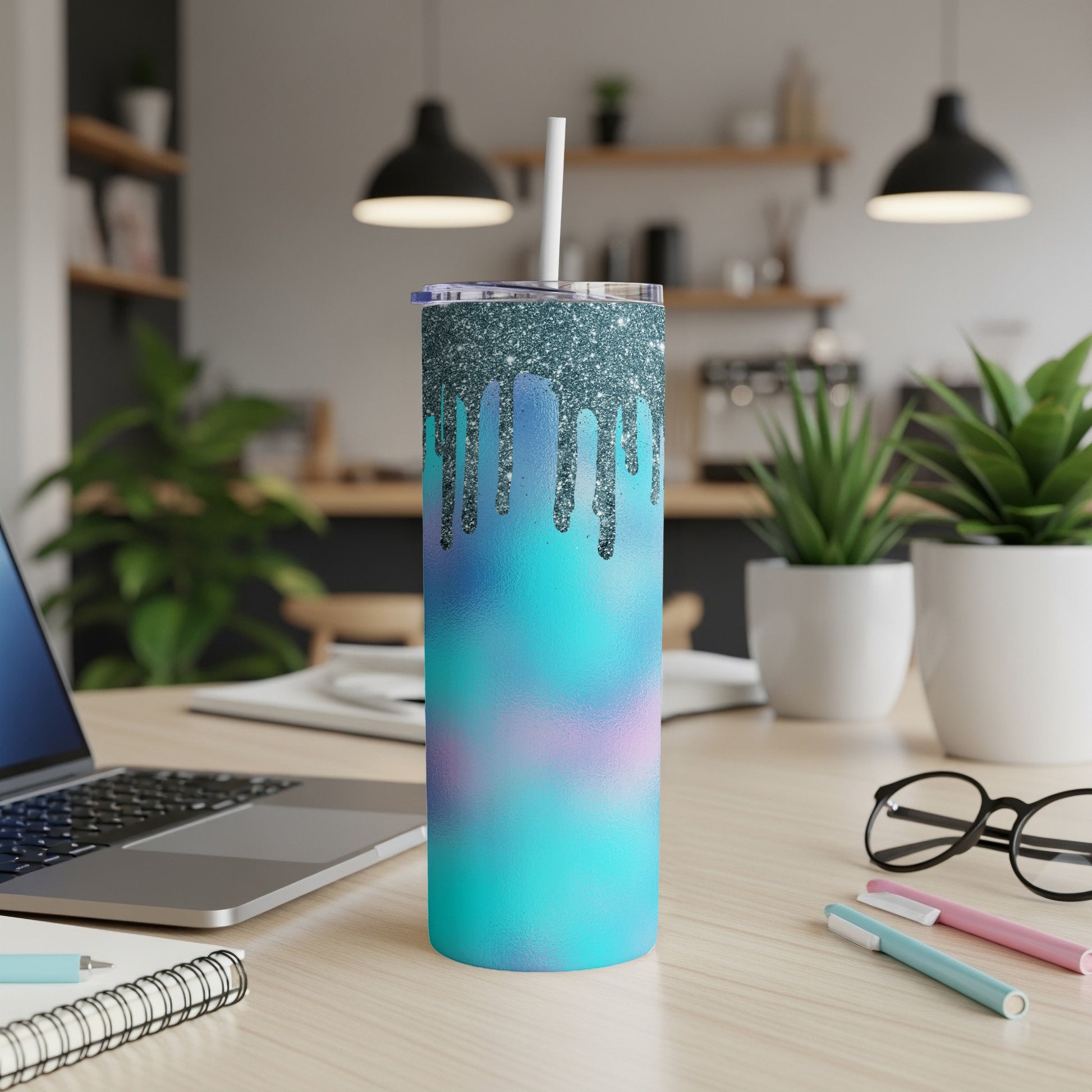 Glittery tumbler with colorful drip design and straw on a desk.