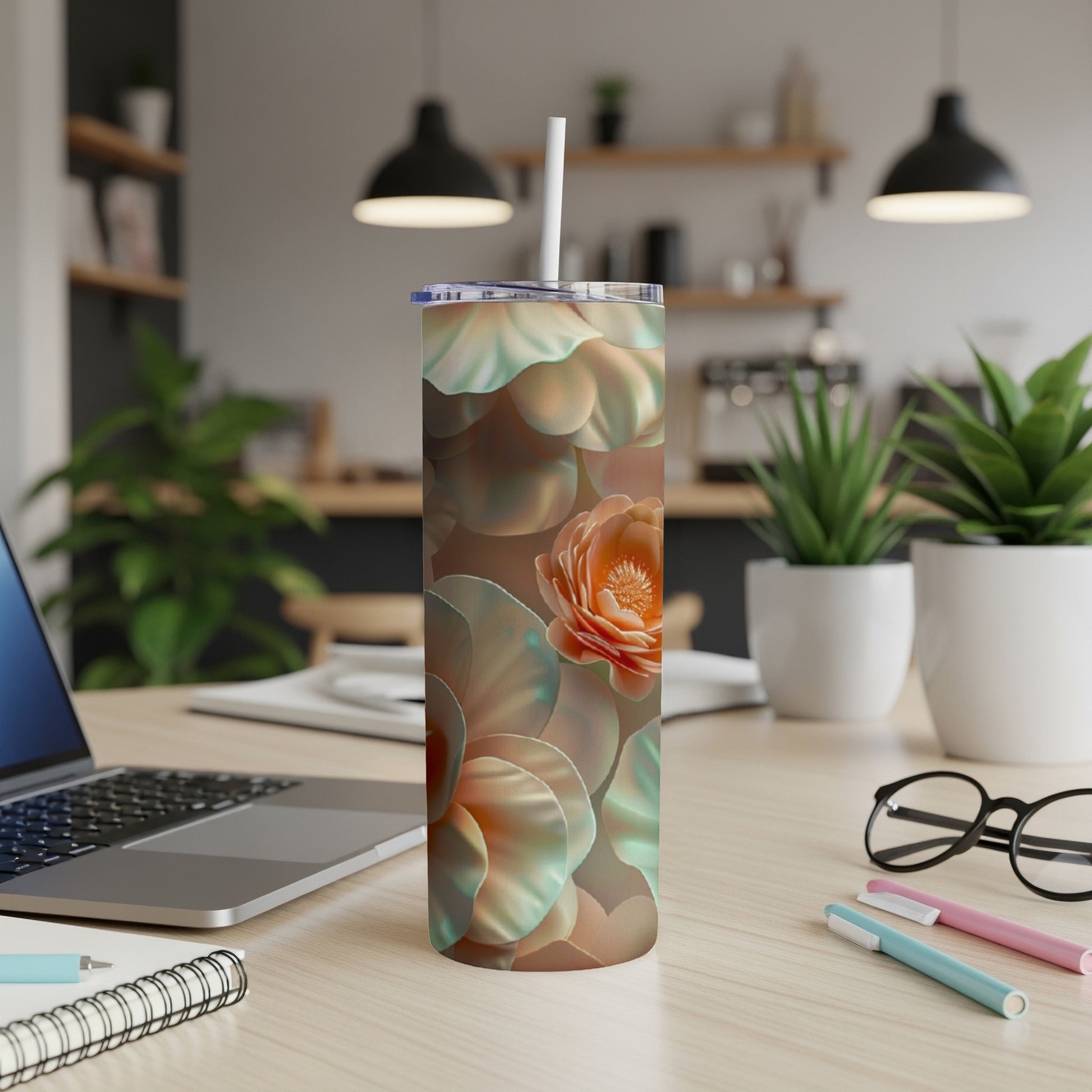 Floral pattern tumbler with straw on a desk next to a laptop.