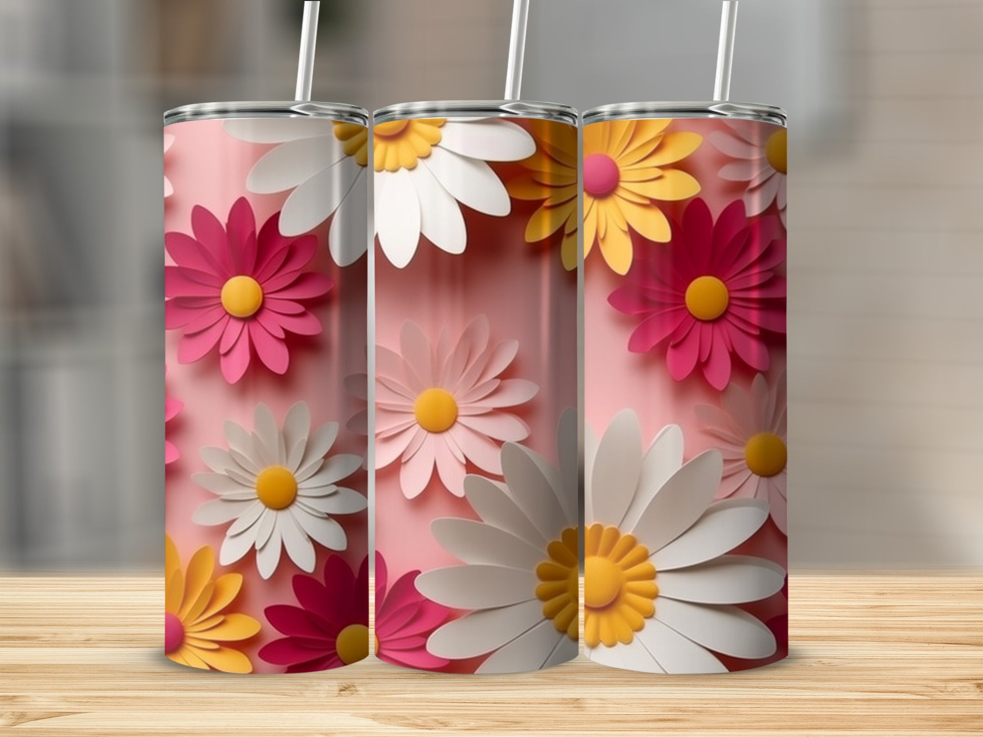 Three pink tumblers decorated with colorful daisy patterns on a wooden surface.