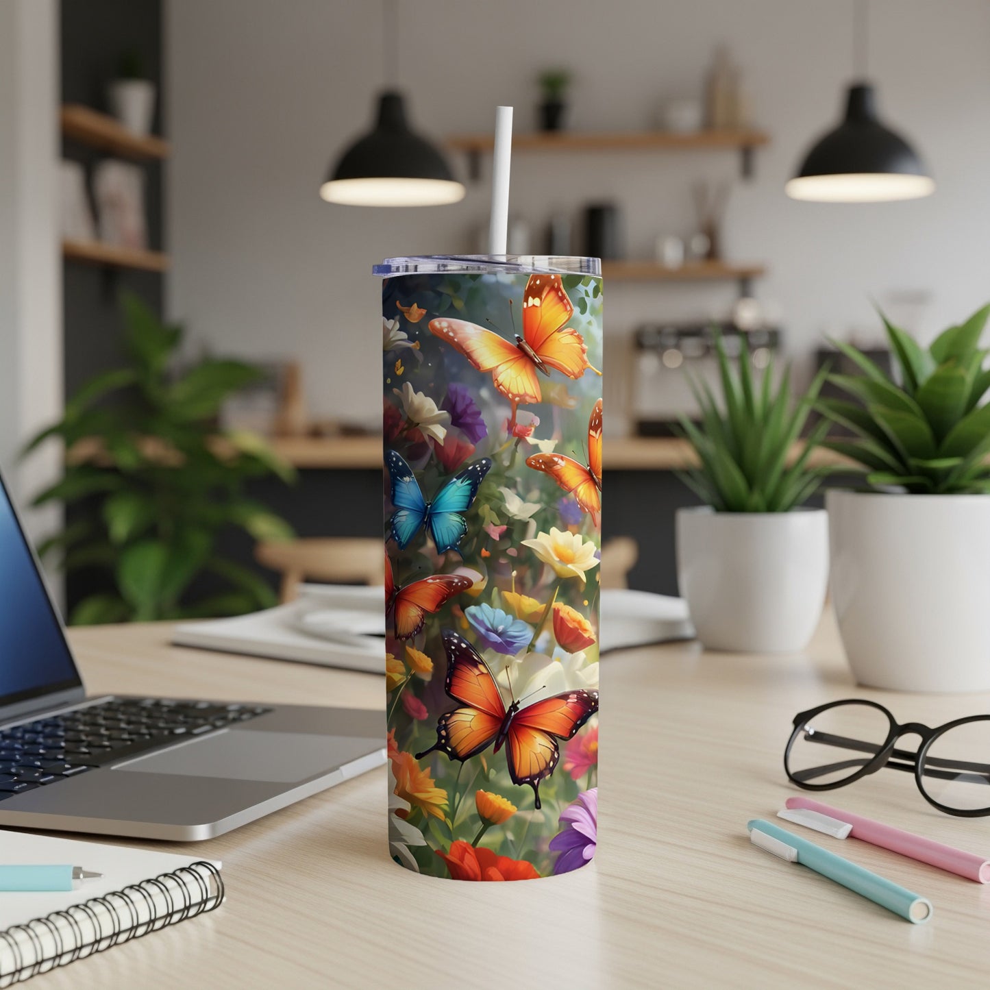 Floral tumbler with vibrant butterflies and a straw on a desk.