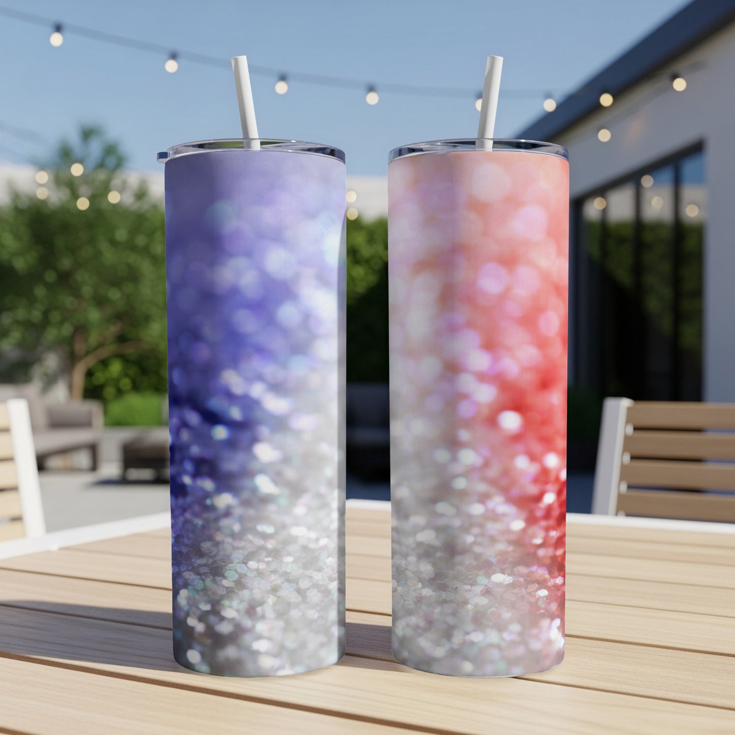 Two glitter tumblers, one blue and one pink, on a table outdoors.