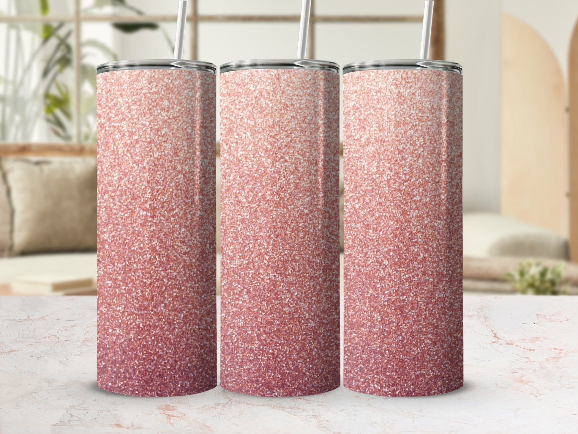 Three rose gold glitter tumblers with straws on a marble surface.