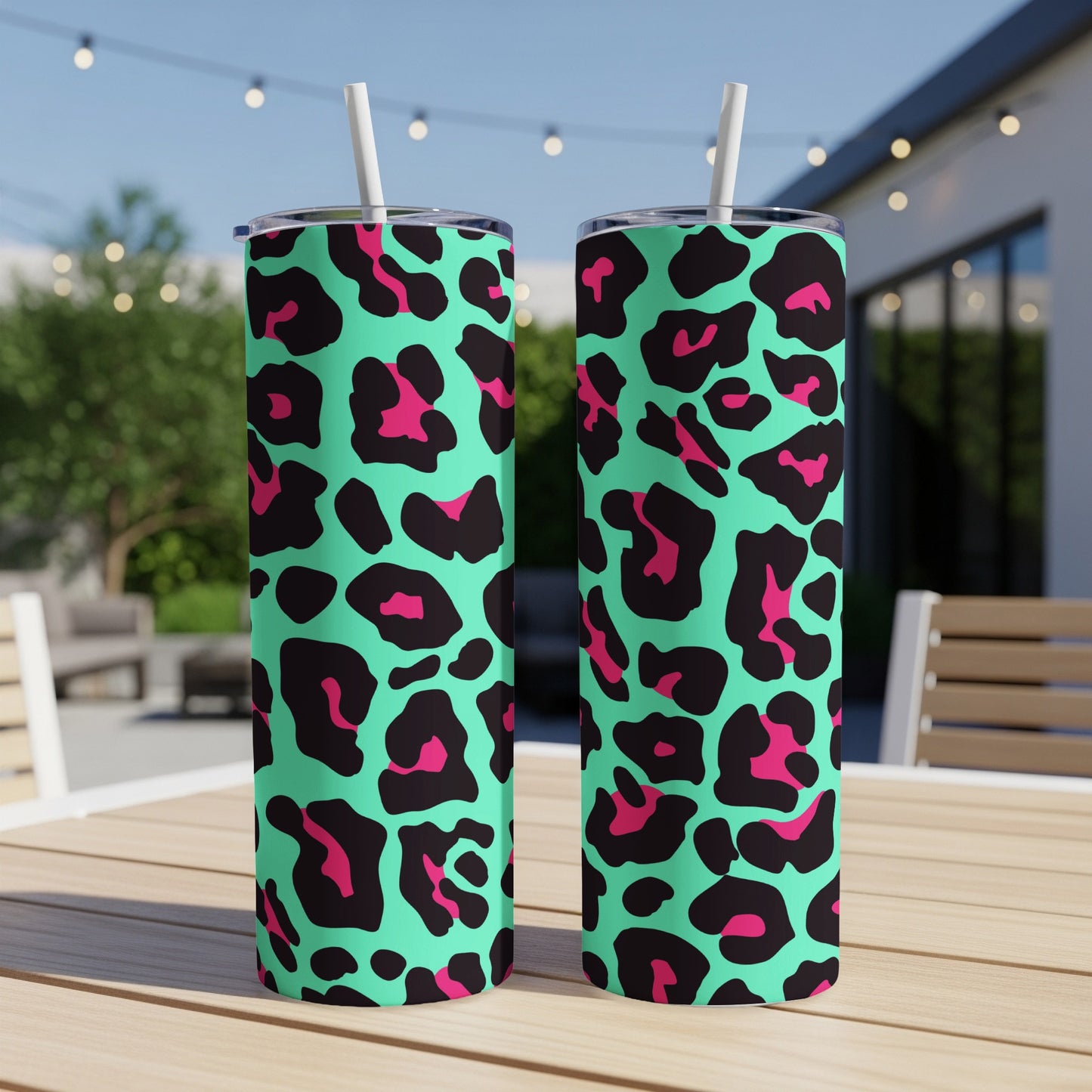 Two teal tumblers with black and hot pink leopard print and white straws.