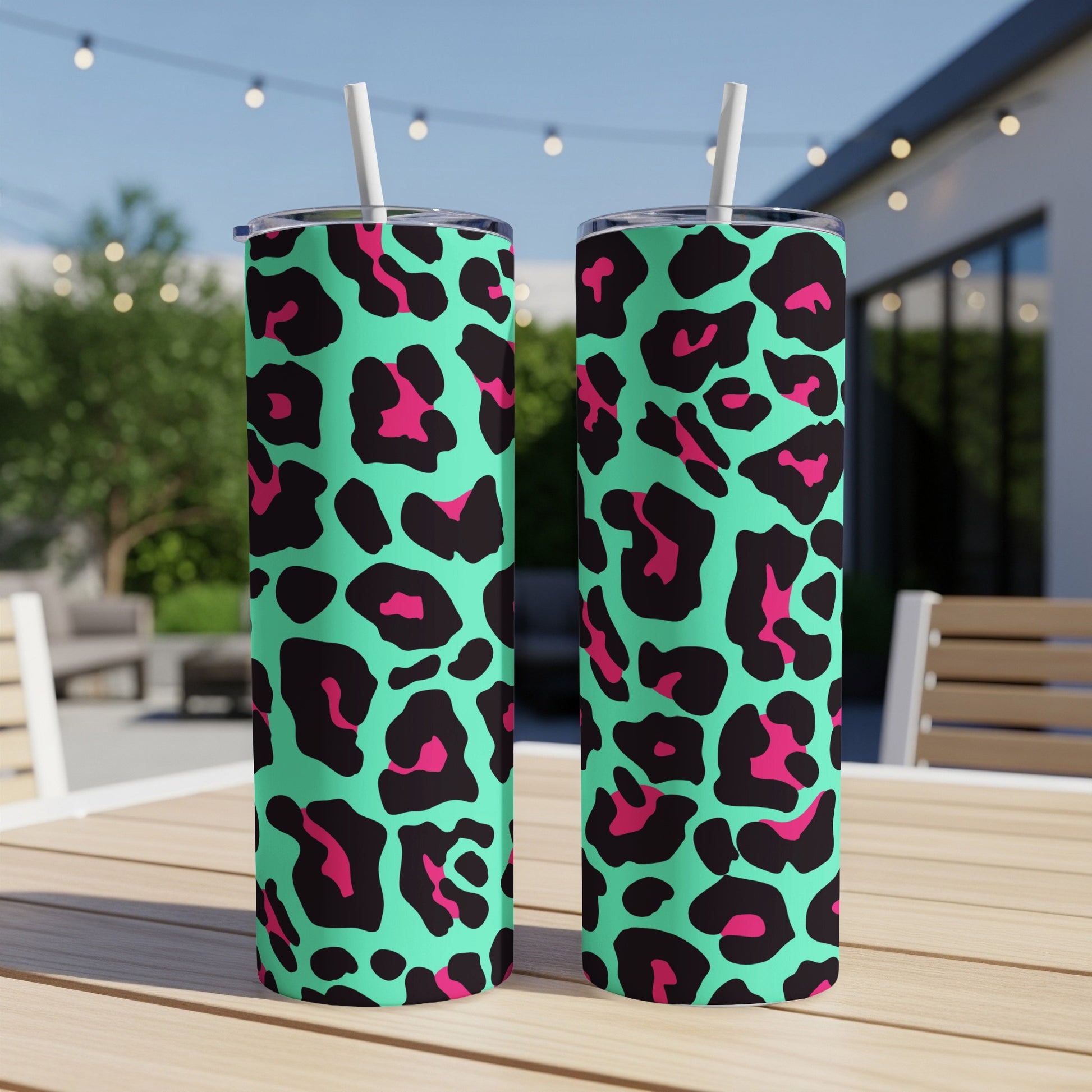 Two teal tumblers with black and hot pink leopard print and white straws.