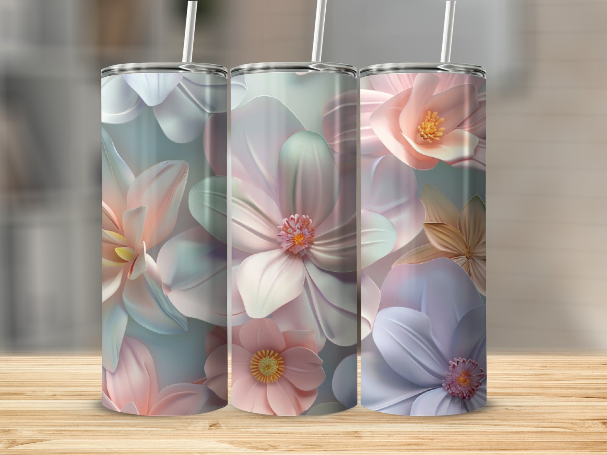 Three pastel floral tumblers with straws on a wooden surface.