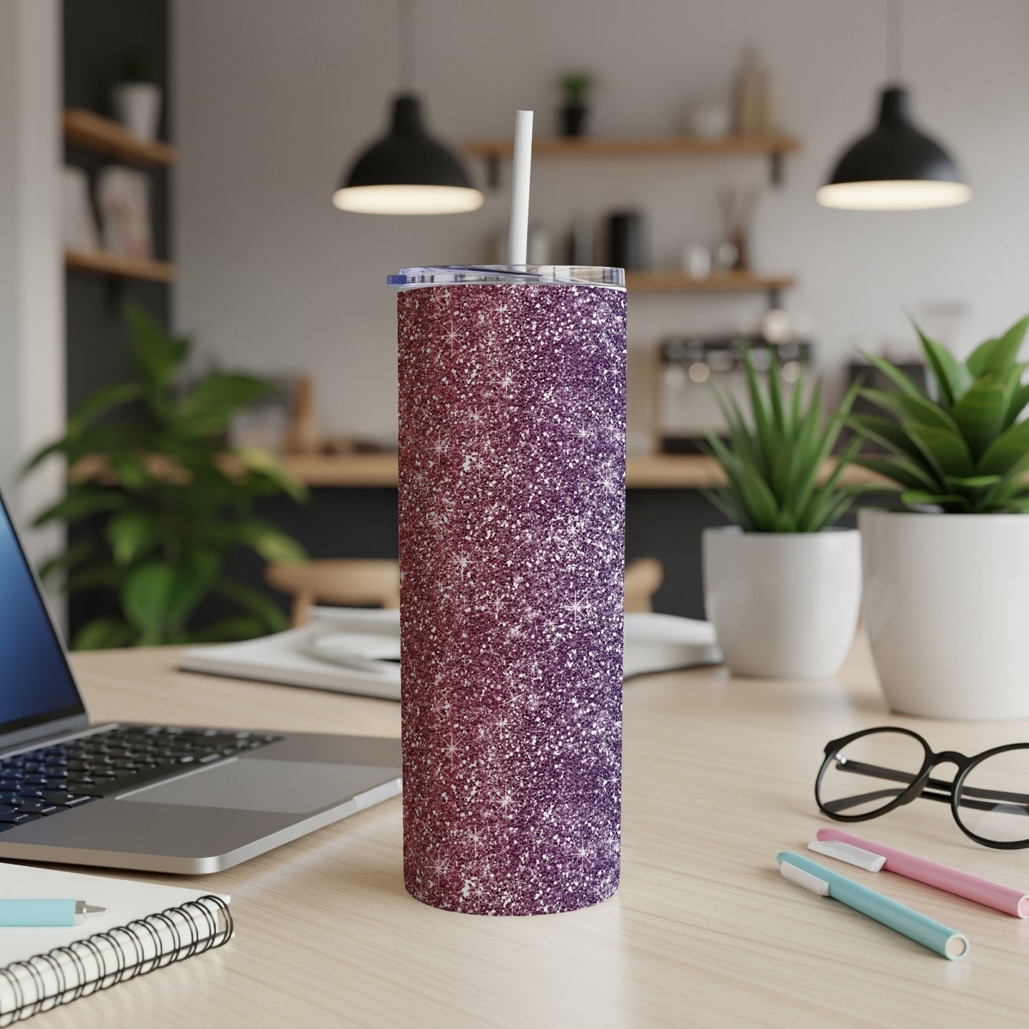 Glitter tumbler with white straw on a desk next to a laptop.