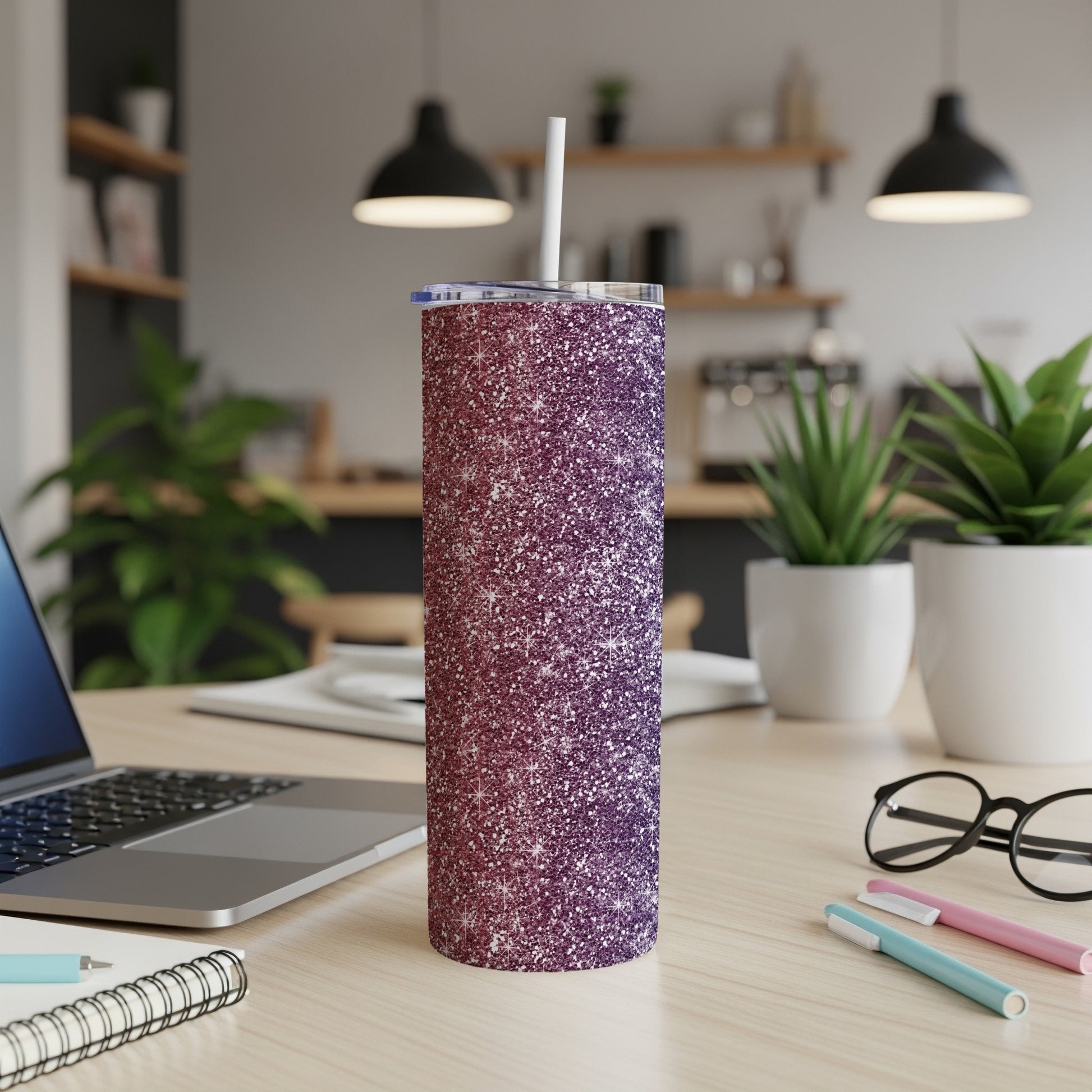Glitter tumbler with white straw on a desk next to a laptop.