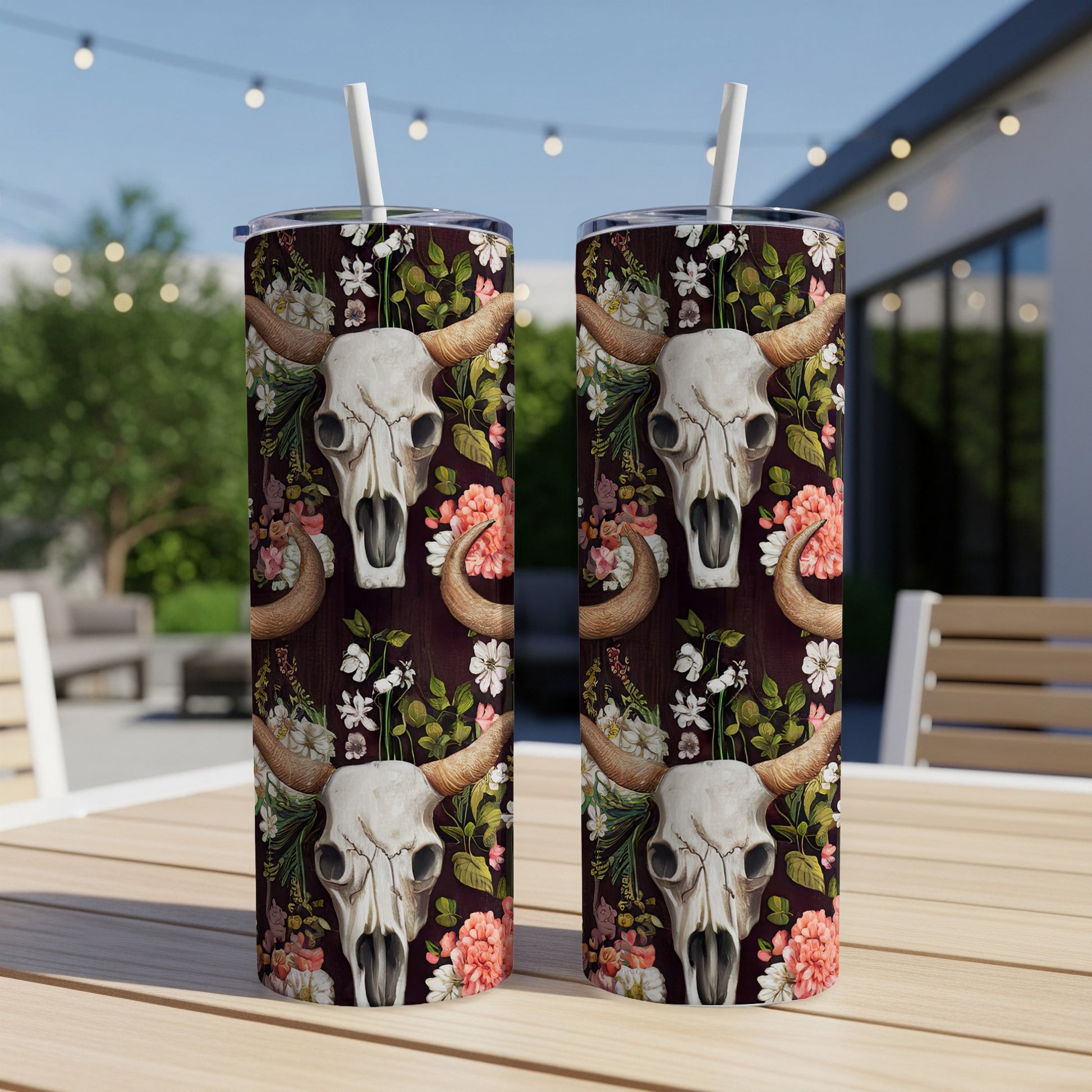 Two tumblers with cow skull and floral pattern on a wooden table.