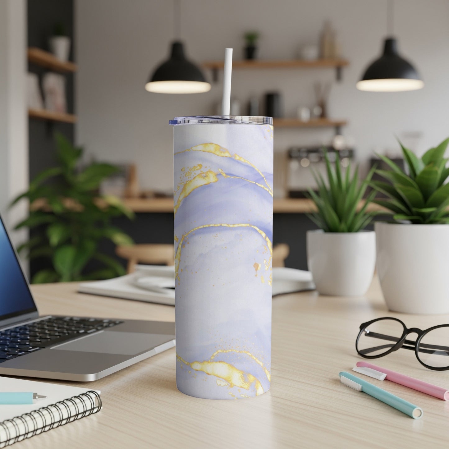 Tall, marbled tumbler with purple and gold design, straw inserted, on a desk.