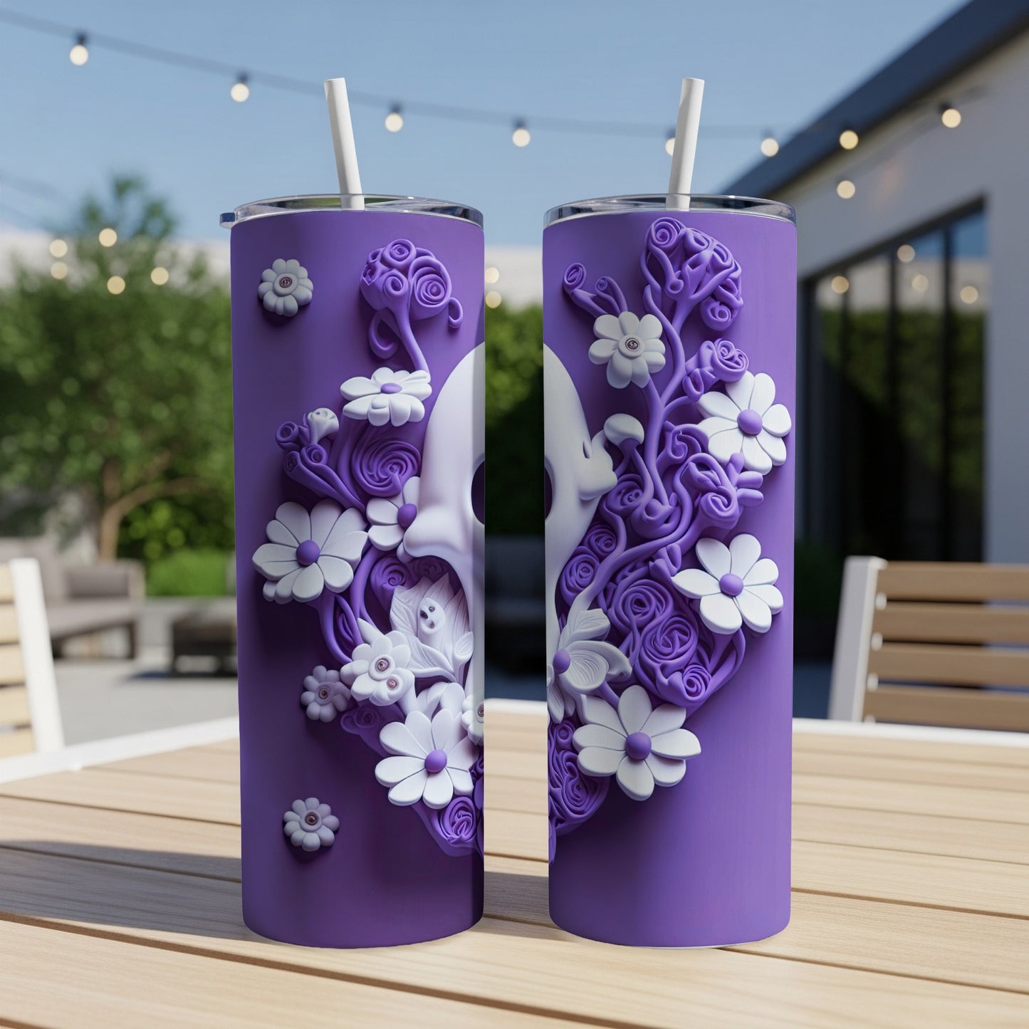 Two purple tumblers with white floral skull designs and straws on a wooden table.