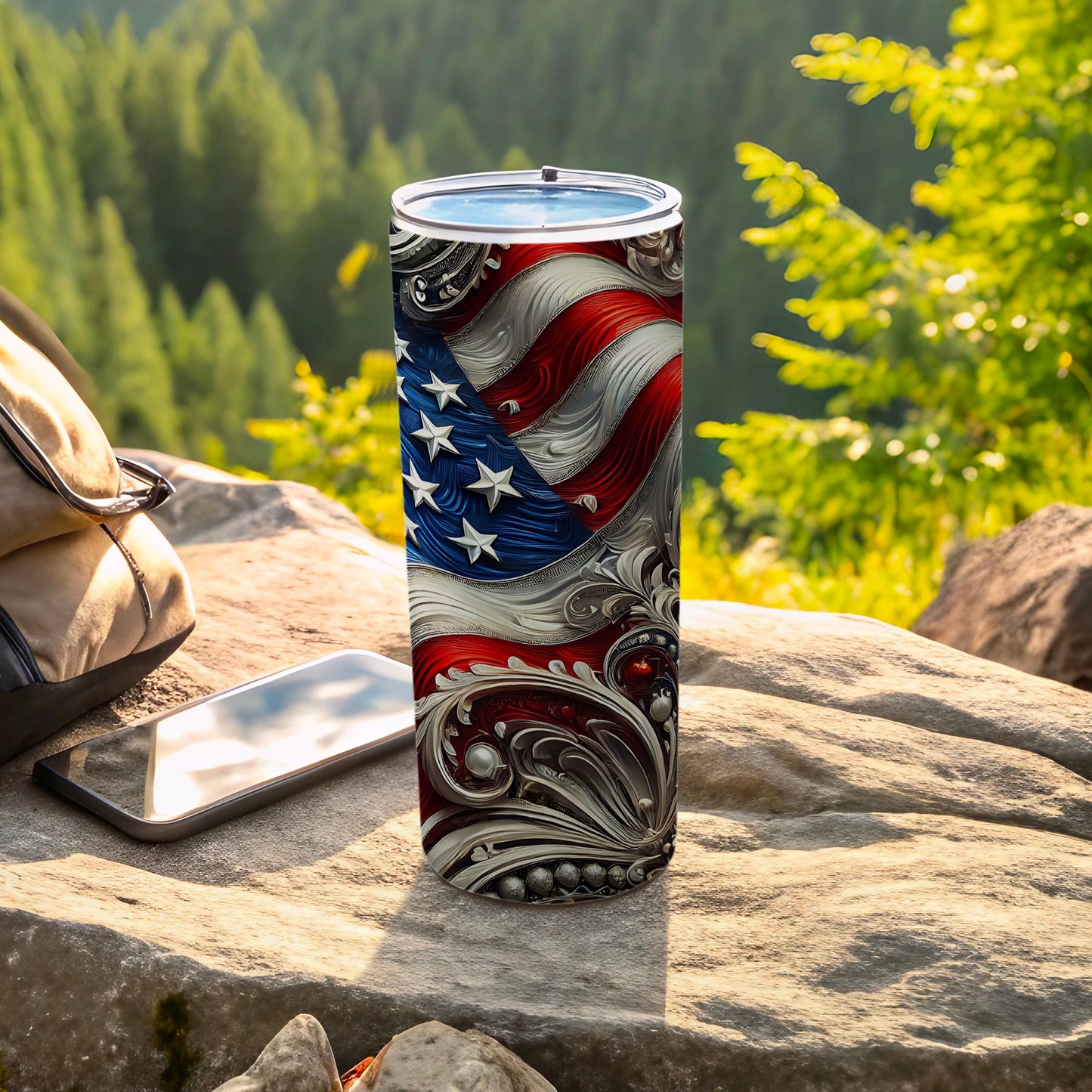 Tumbler with American flag design and ornate silver scrollwork on a rocky outdoor surface.
