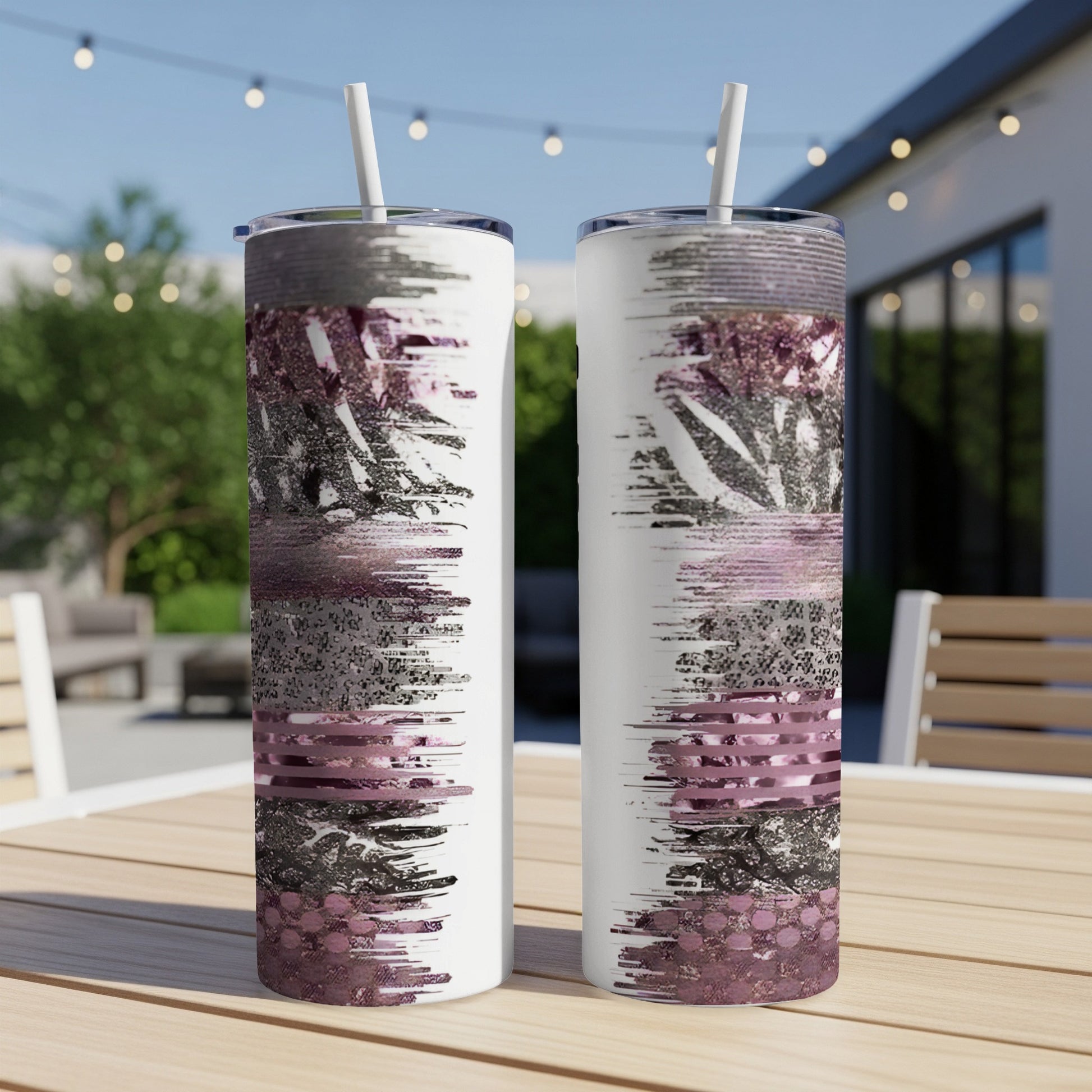 Two white tumblers with textured pink and silver abstract design on an outdoor table.