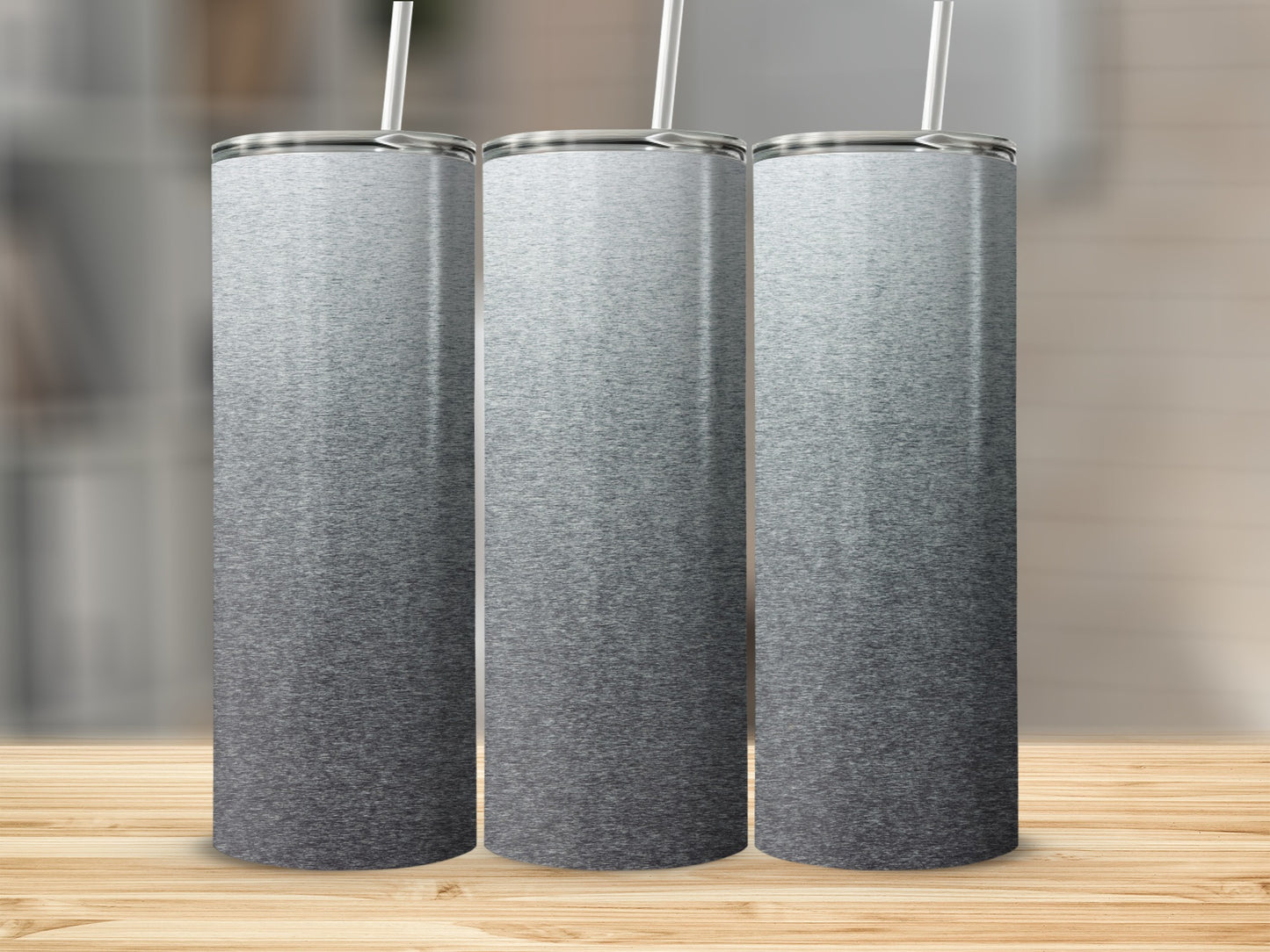 Three tall, stainless steel tumblers with a gray ombre design sit on a wooden surface.