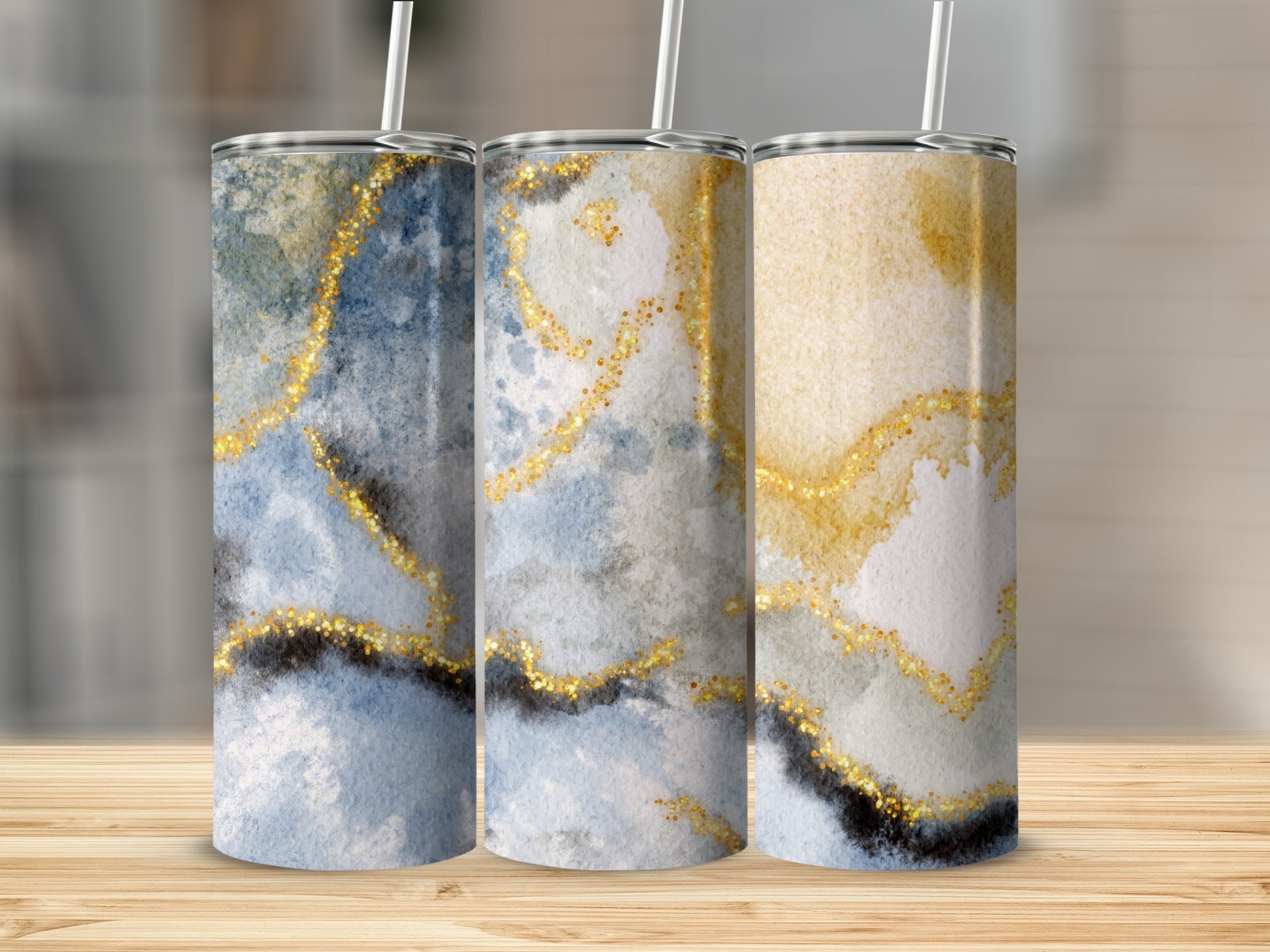 Three tumblers with blue and gold marbled watercolor designs and glitter accents.