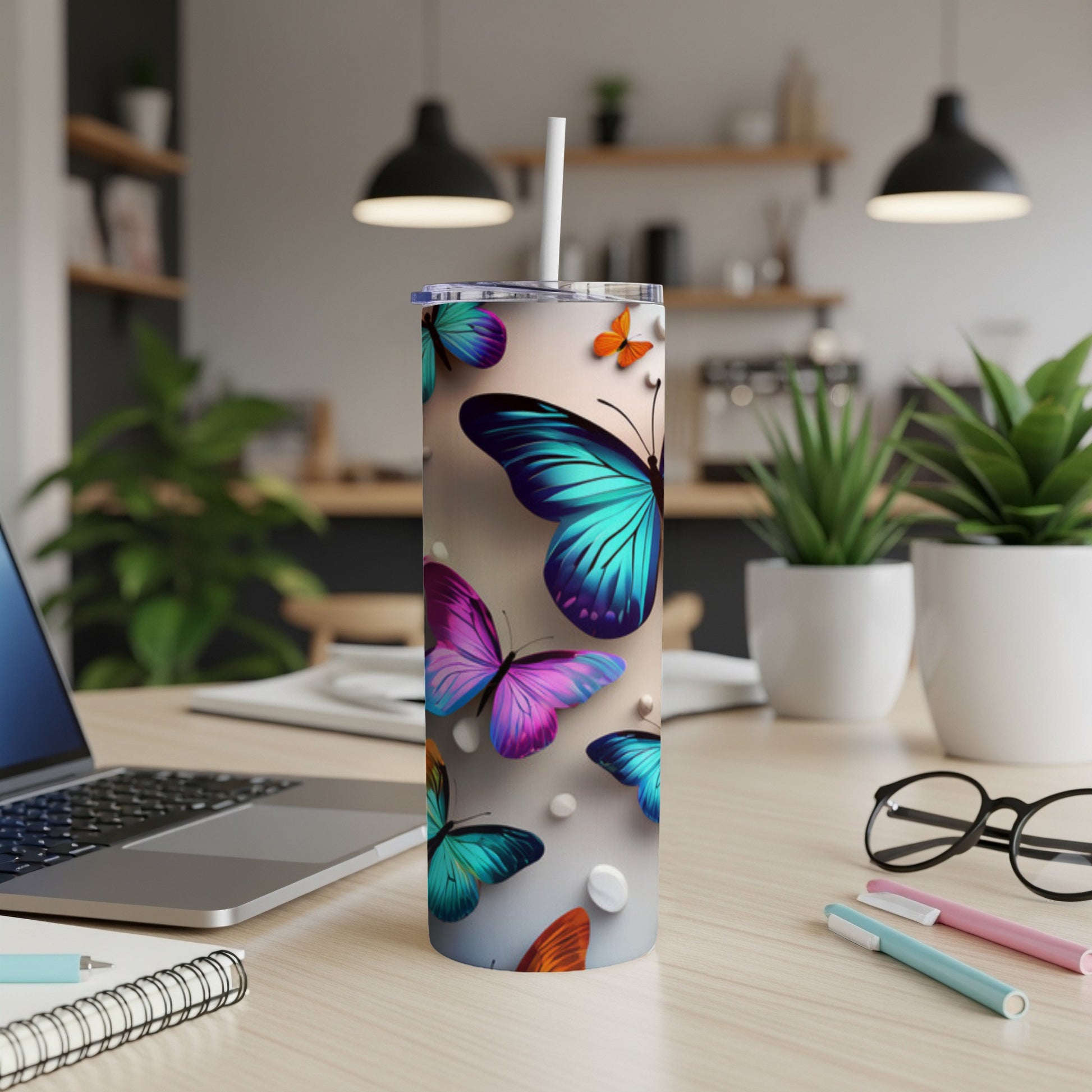 Tumbler with colorful butterflies and a white straw on a desk.